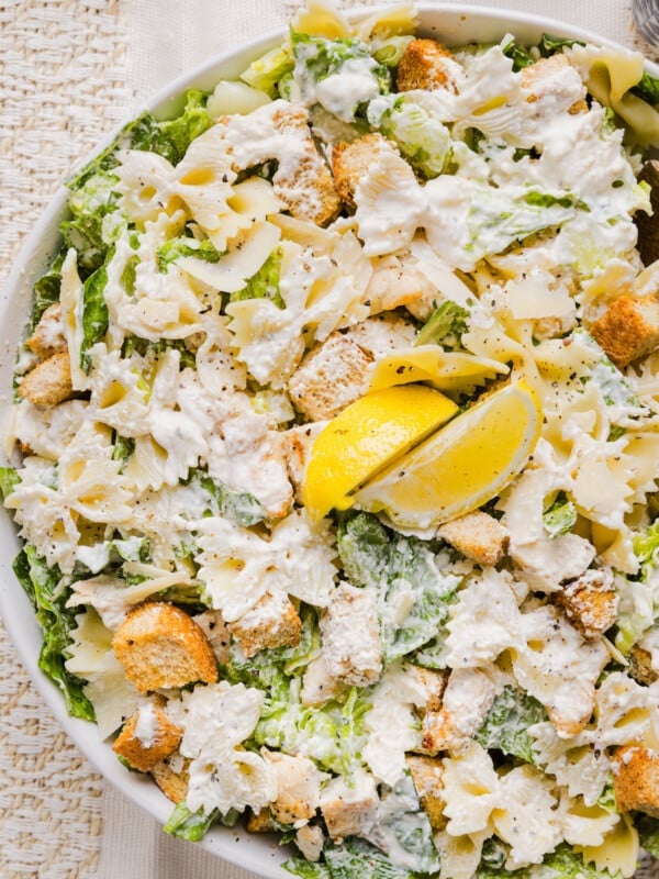 Chicken caesar pasta salad in a large bowl garnished with lemon.