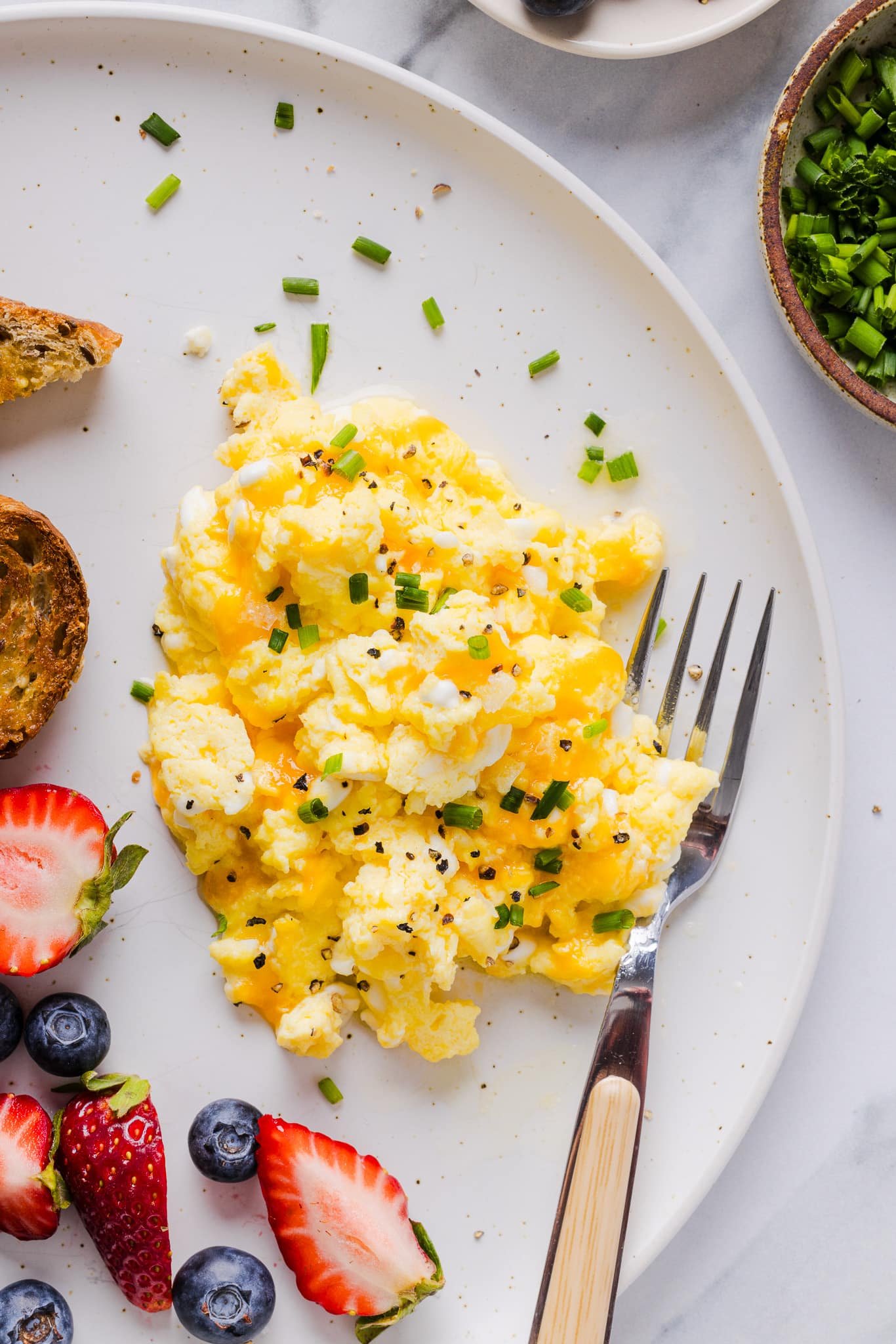 Cottage cheese eggs garnished with chives on a white plate.