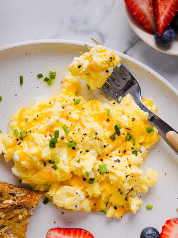 Cottage cheese eggs garnished with chives on a white plate.