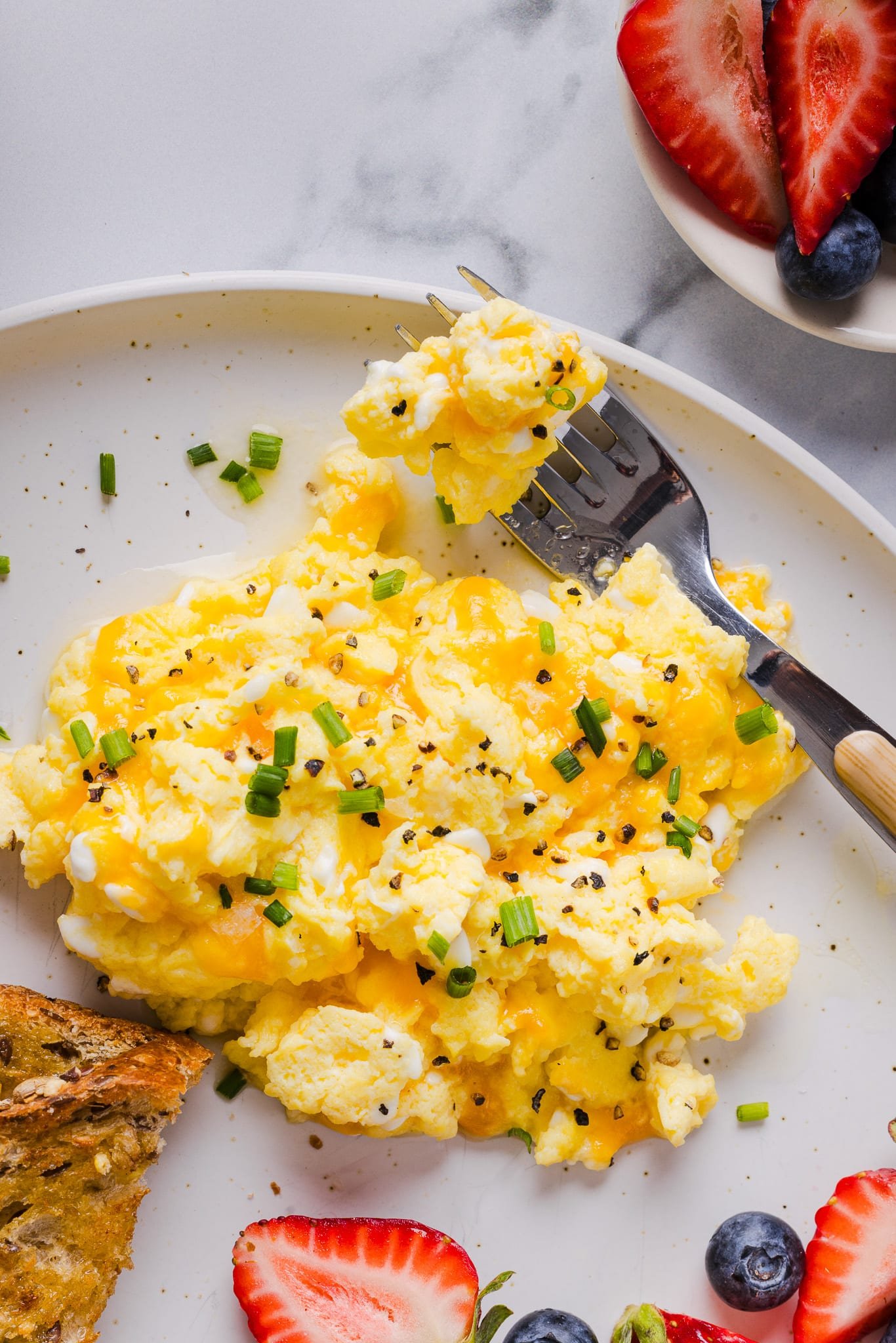 Cottage cheese eggs garnished with chives on a white plate.