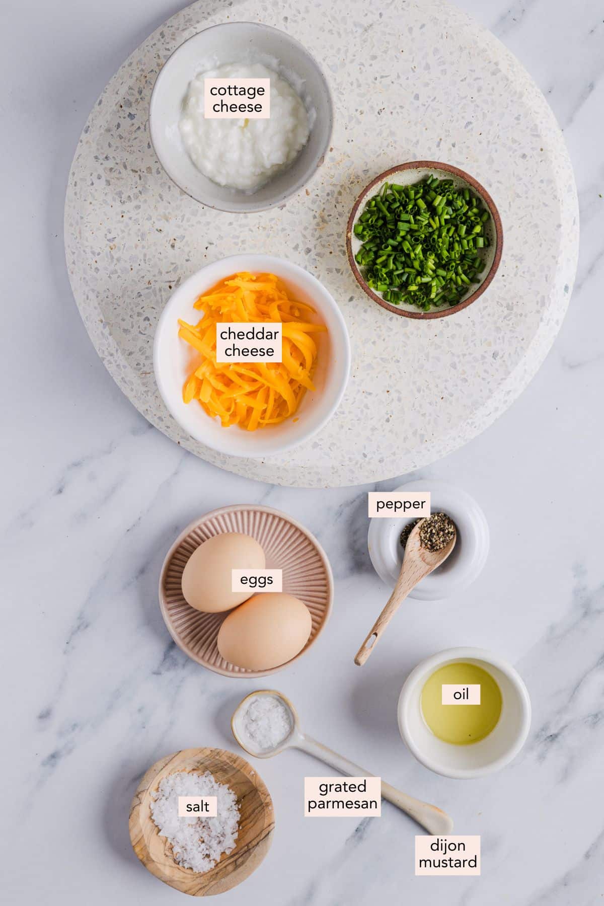 Ingredients for cottage cheese eggs in small bowls on a countertop with labels.