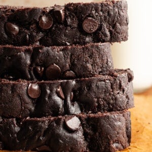 Slices of healthy chocolate zucchini bread stacked on a wooden board.