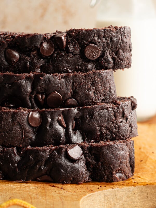 Slices of healthy chocolate zucchini bread stacked on a wooden board.