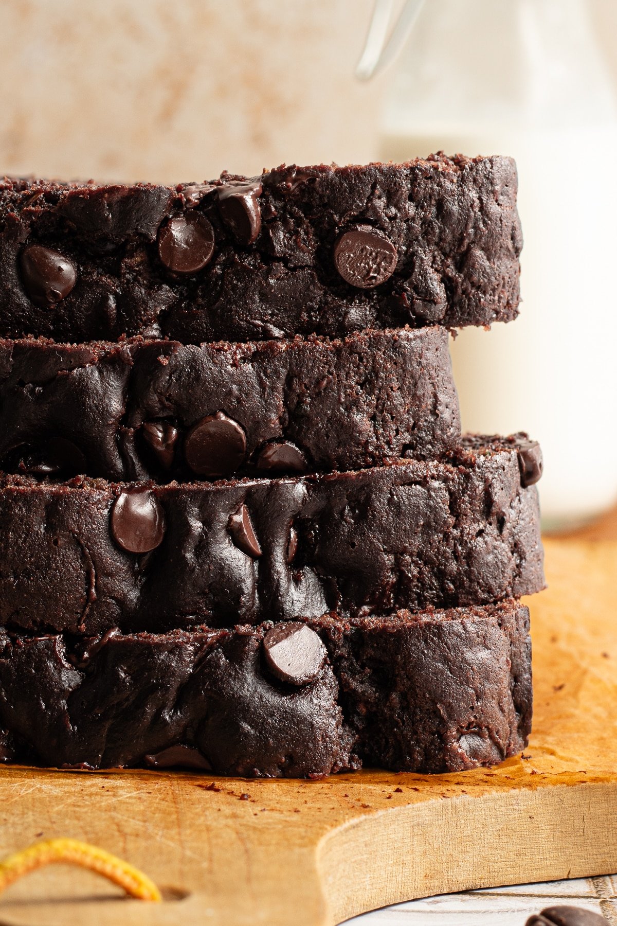 Slices of healthy chocolate zucchini bread stacked on a wooden board.
