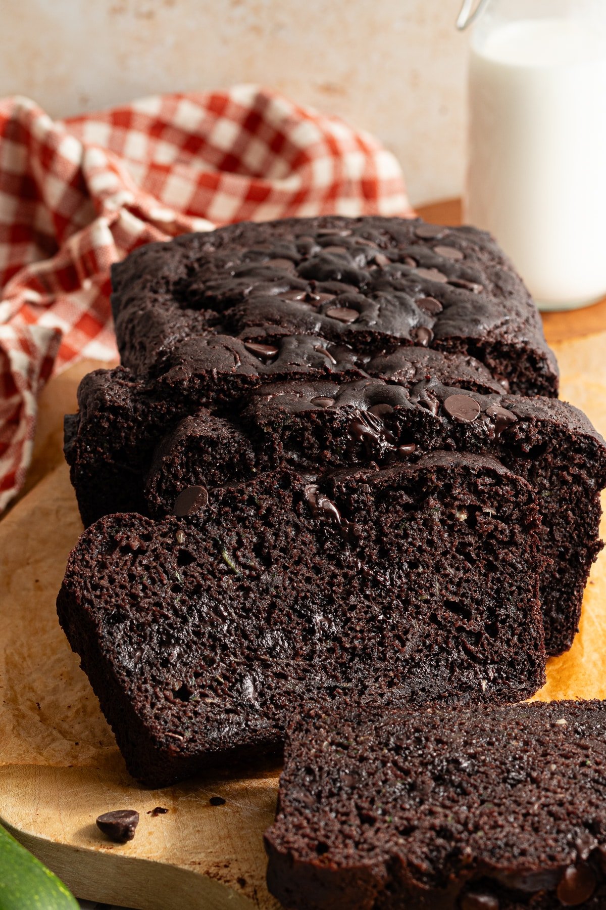 A loaf of sliced healthy chocolate zucchini bread on a wooden board.