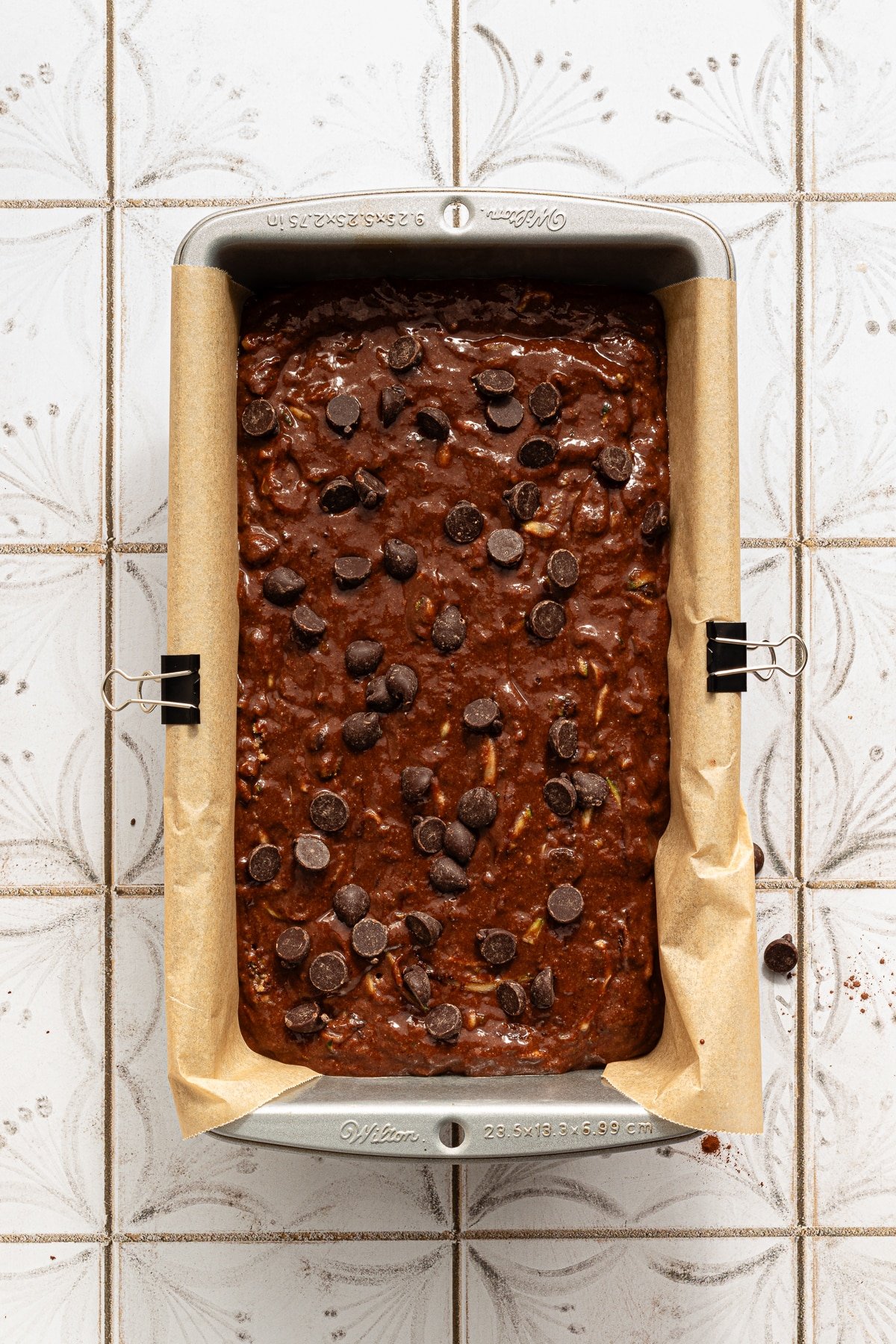 Healthy chocolate zucchini bread poured in a loaf pan and topped with chocolate chips.