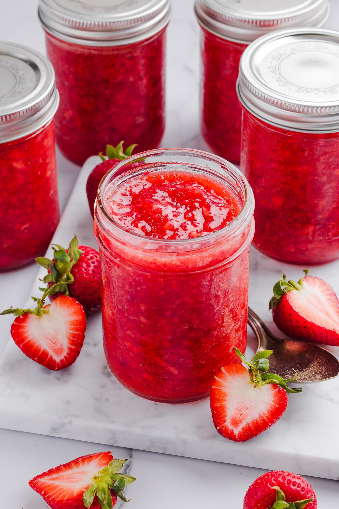 Low sugar strawberry freezer jam in jars on a marble slab.