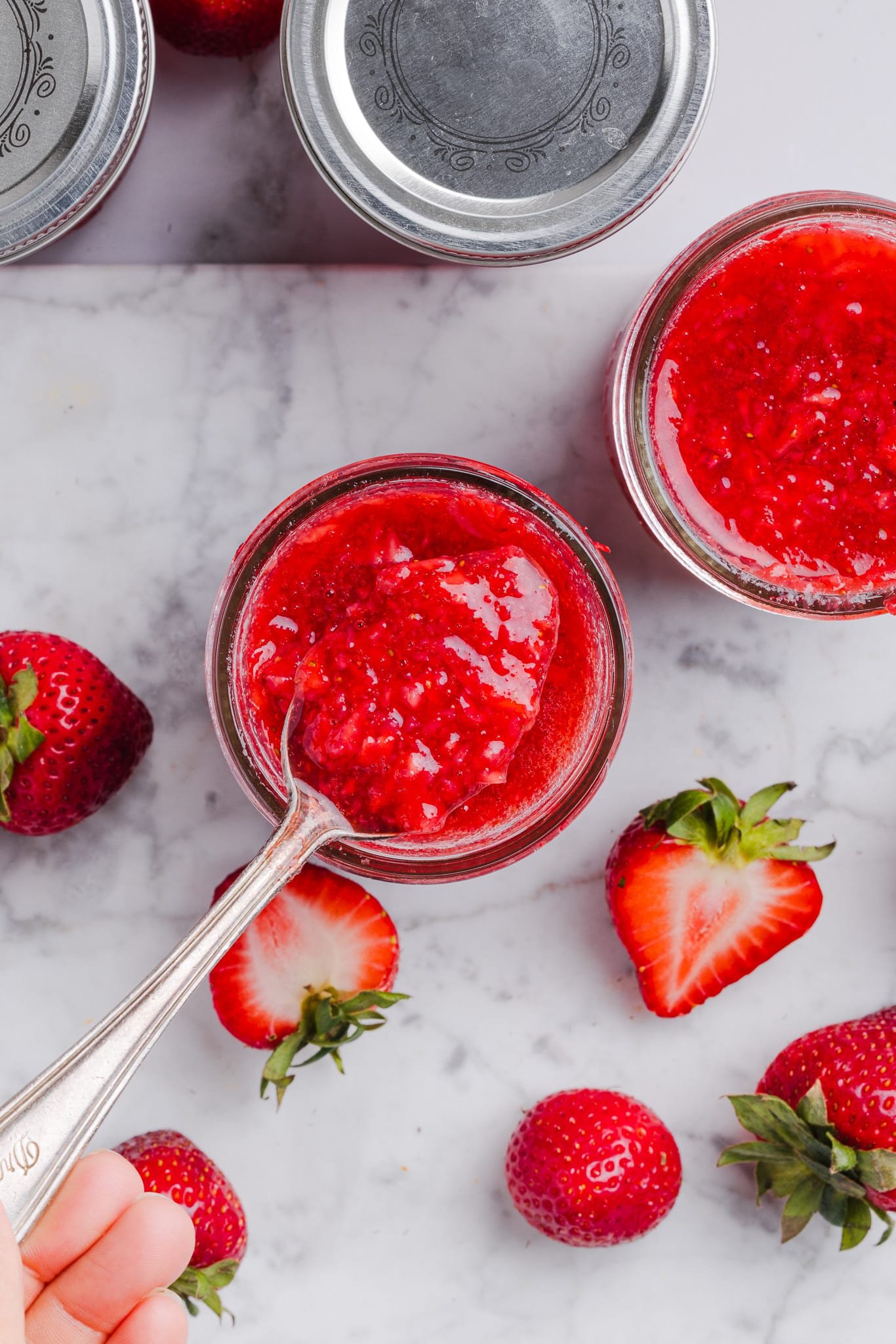 A spoonful of low sugar strawberry freezer jam above a jar. 