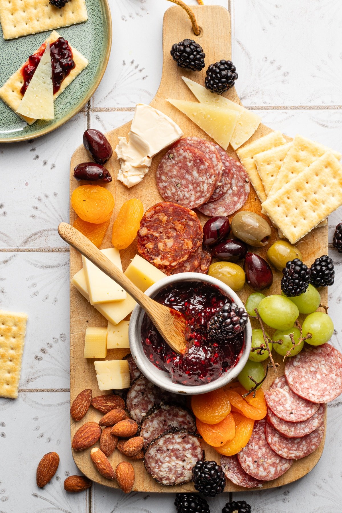 A charcuterie board with meats and cheeses and blackberry freezer jam.