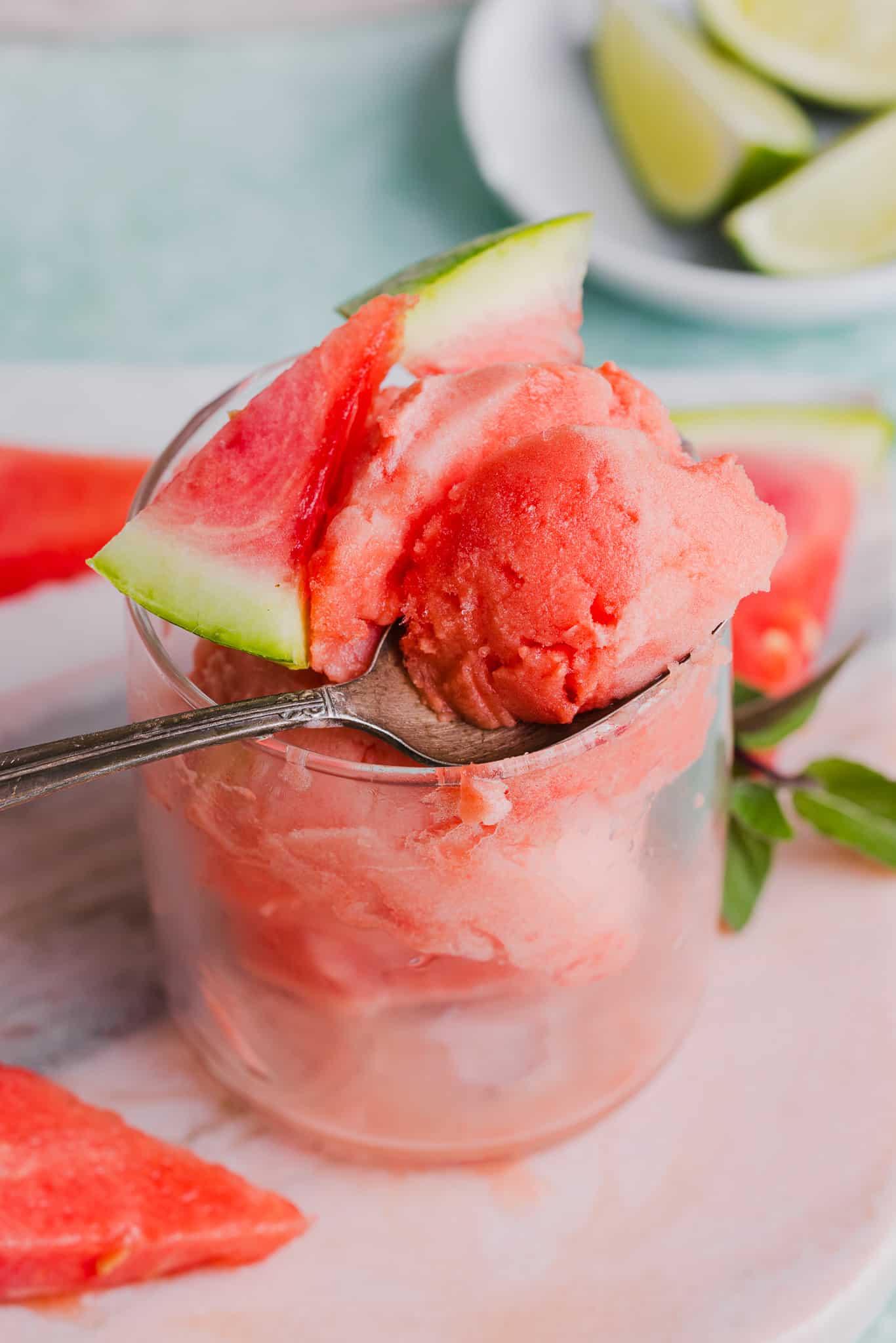 Beat the summer heat with this 3-ingredient watermelon sorbet recipe! Bursting with natural sweetness and a zesty lime twist, it's SO yum! A spoon taking a scoop from a serving of watermelon sorbet.