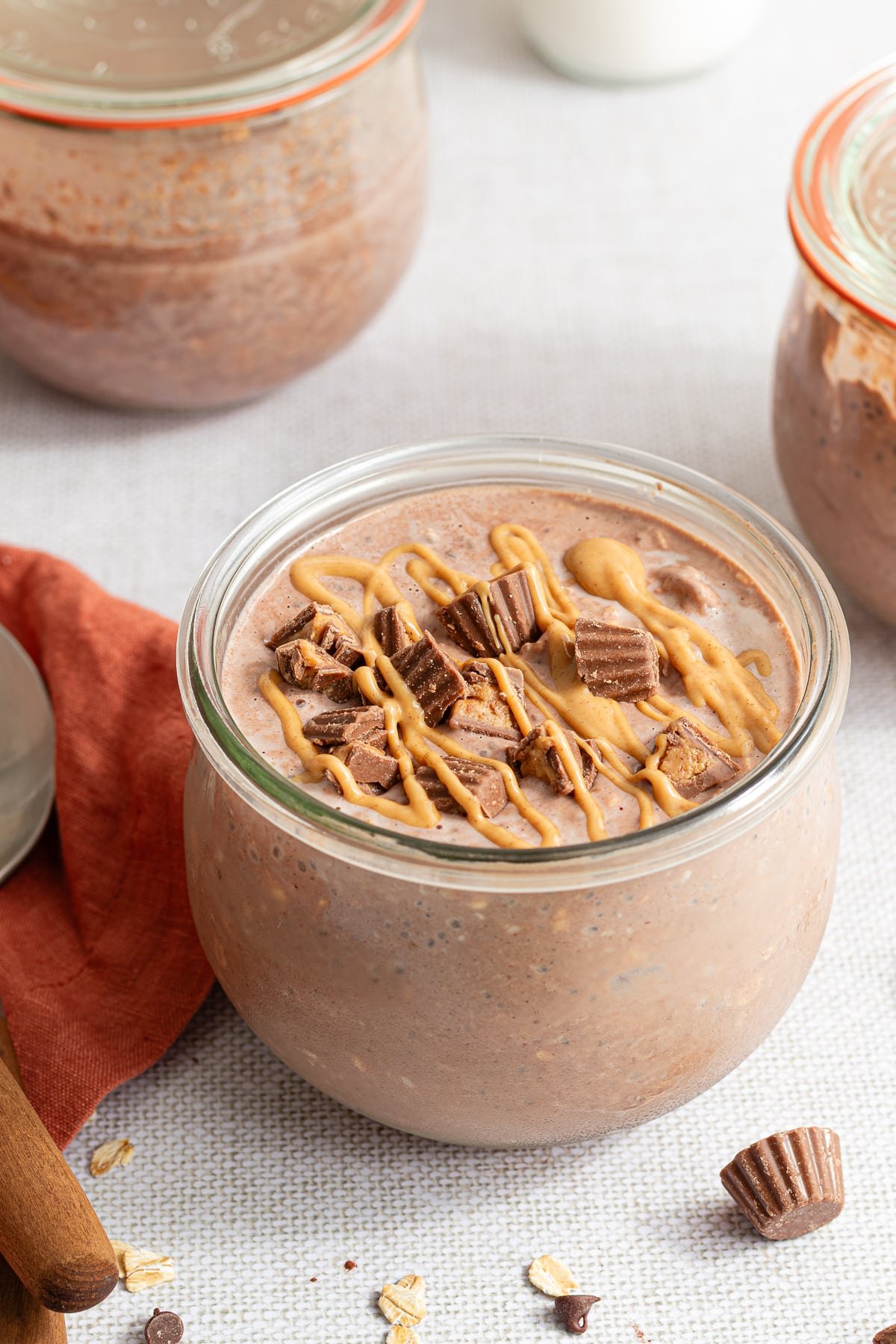 Chocolate peanut butter overnight oats in a jar topped with mini Reese's and a drizzle of peanut butter.