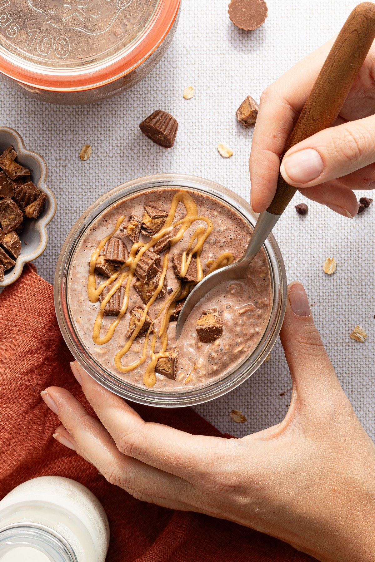Taking a spoonful of chocolate peanut butter overnight oats from a jar.