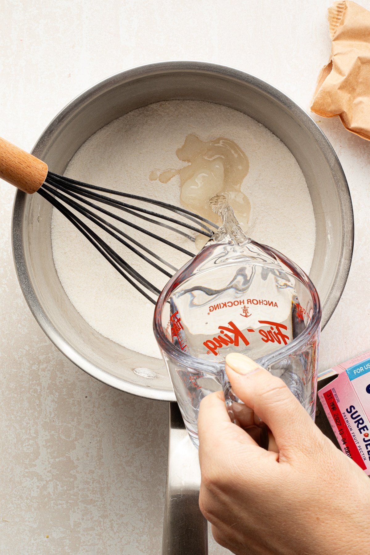 Sugar, pectin and water being poured into a saucepan.