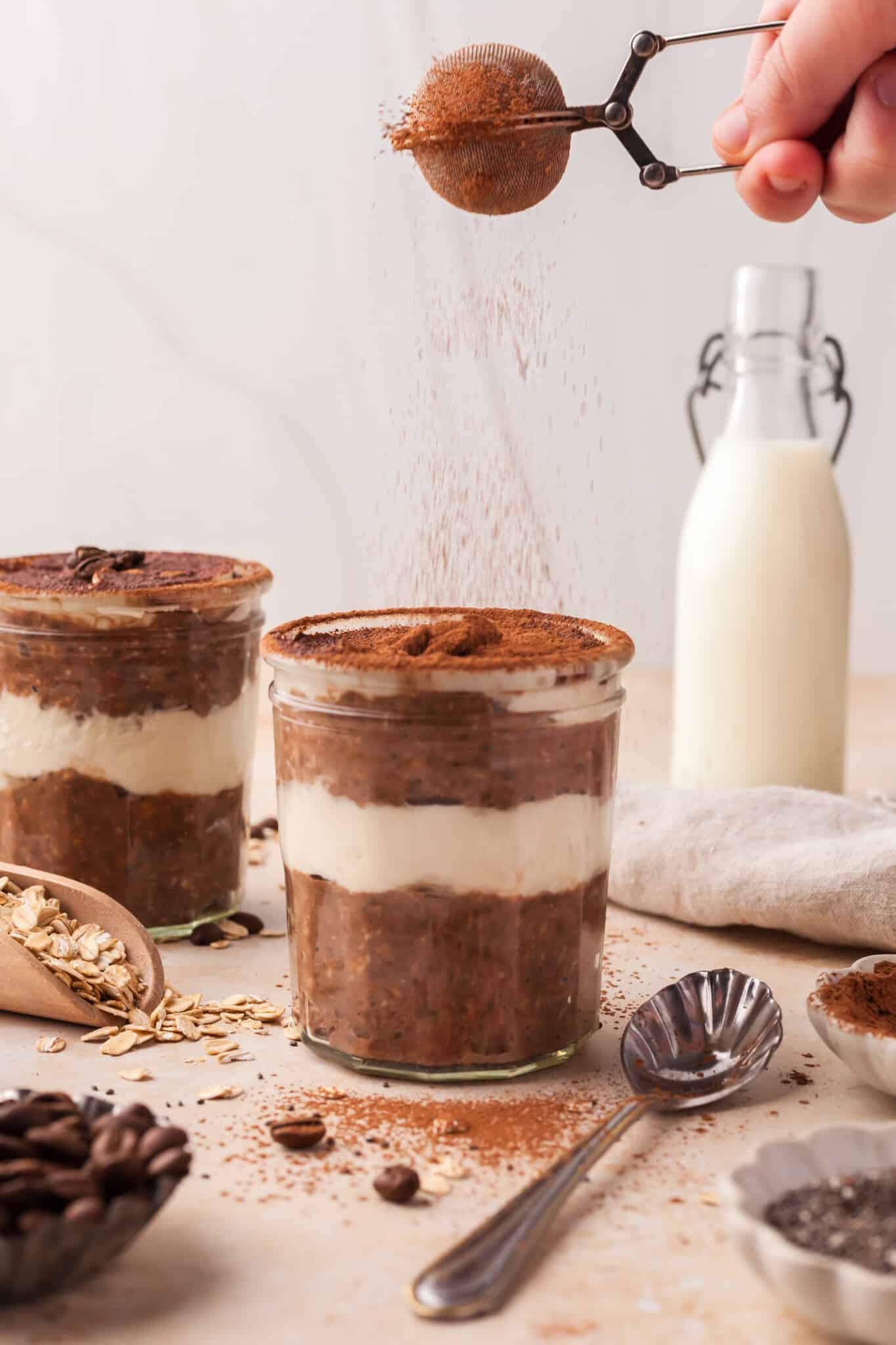 Add a final layer of mascarpone topping to the oats and dust with cocoa powder.