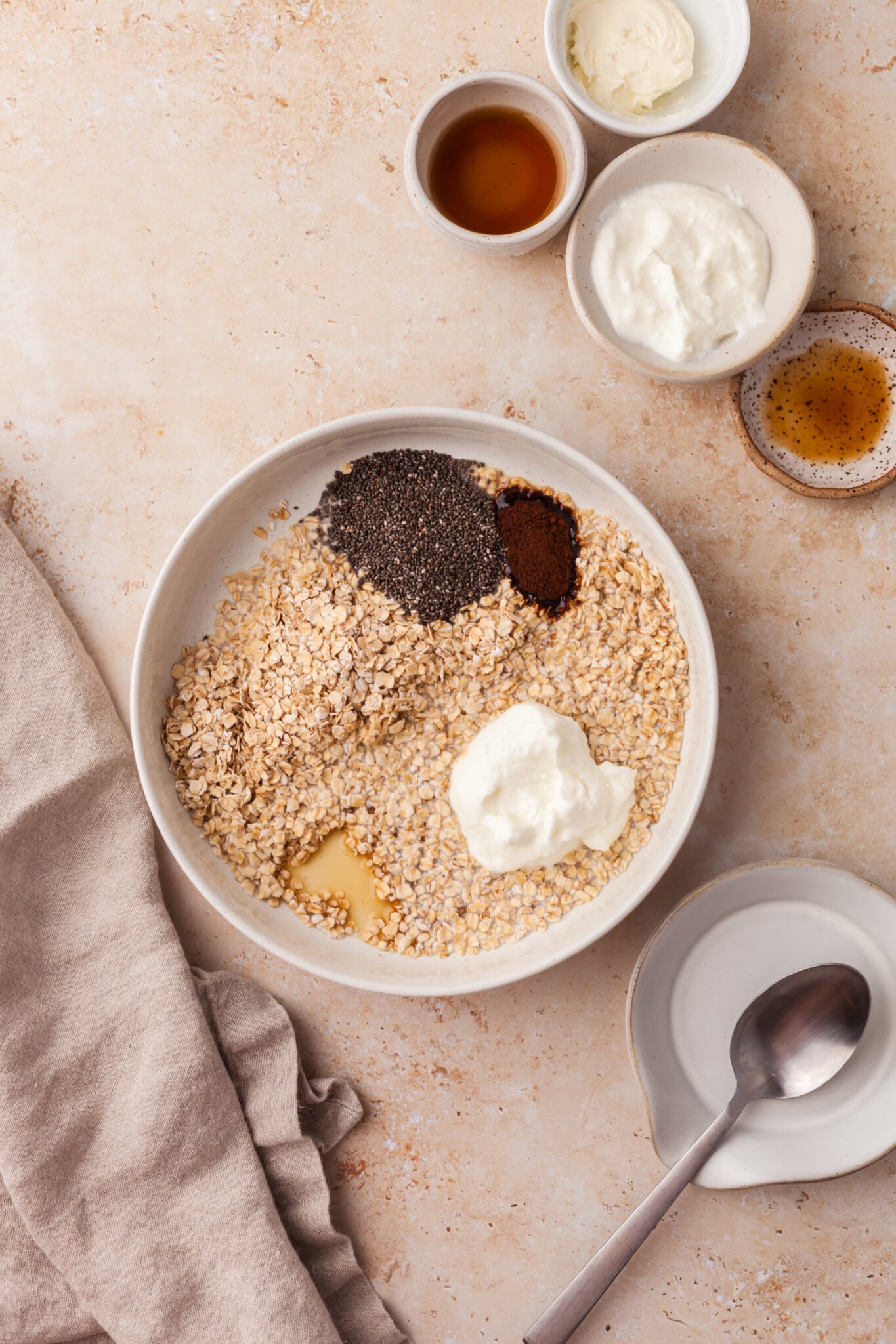 Combining oats, Greek yogurt, milk, chia seeds, instant coffee, and maple syrup in a bowl.