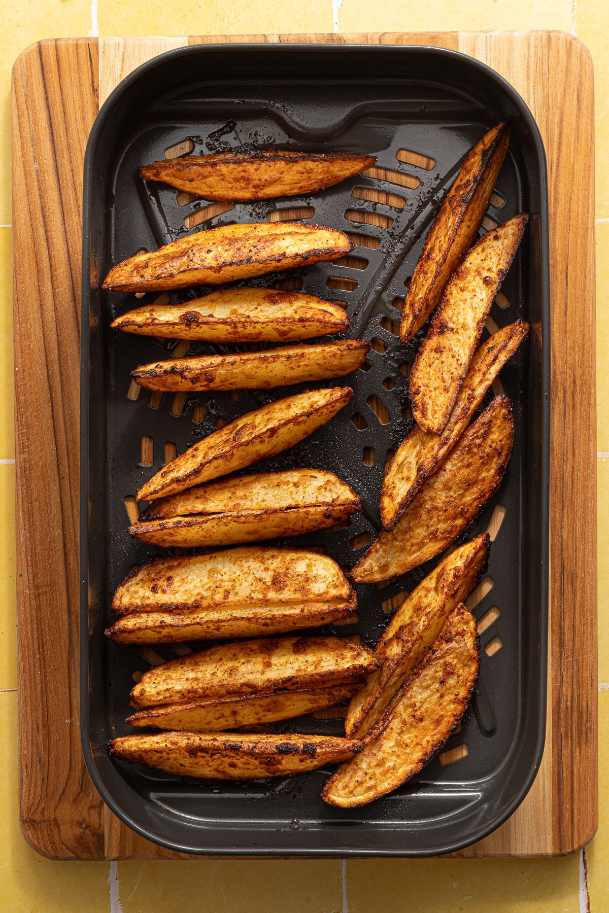 Crispy potato wedges in the basket of an air fryer.
