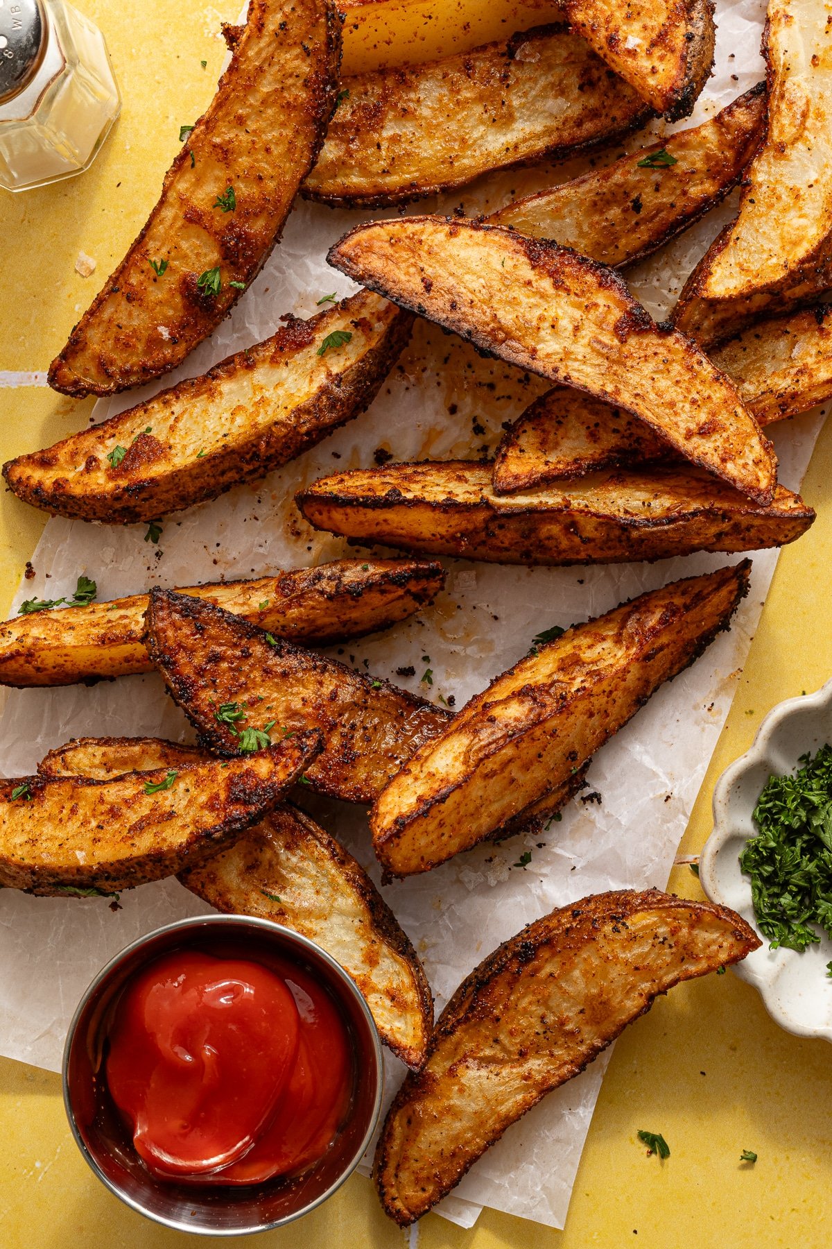 Overhead image of crispy potato wedges with ketchup.