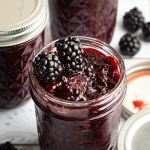 Blackberry jam with two blackberries on top.
