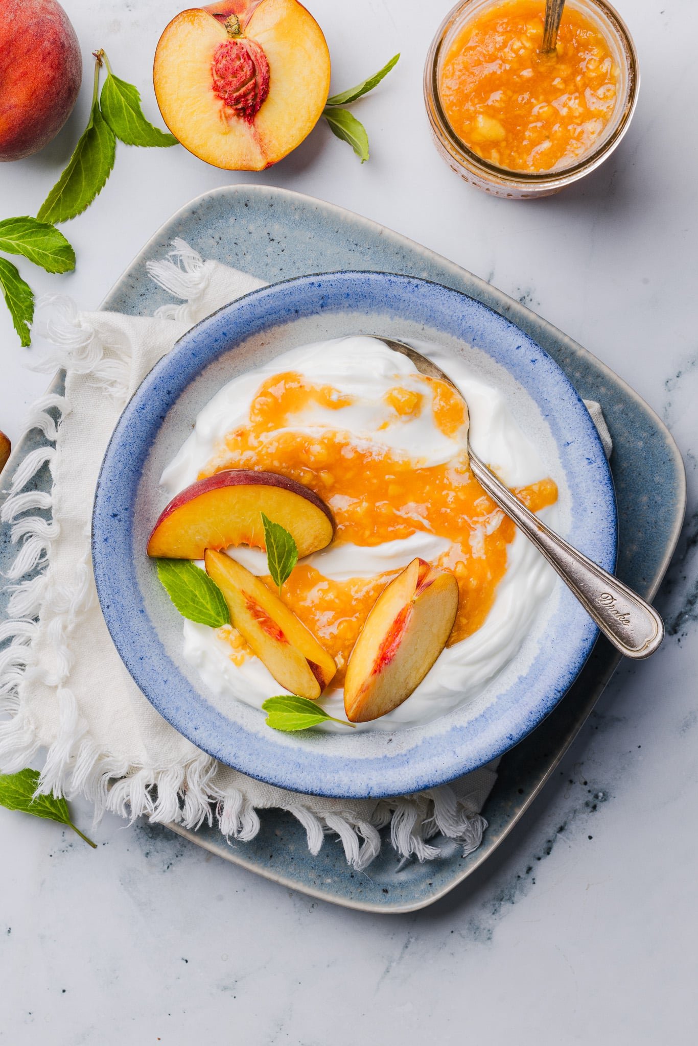 Peach freezer jam swirled into yogurt and topped with fresh peaches.