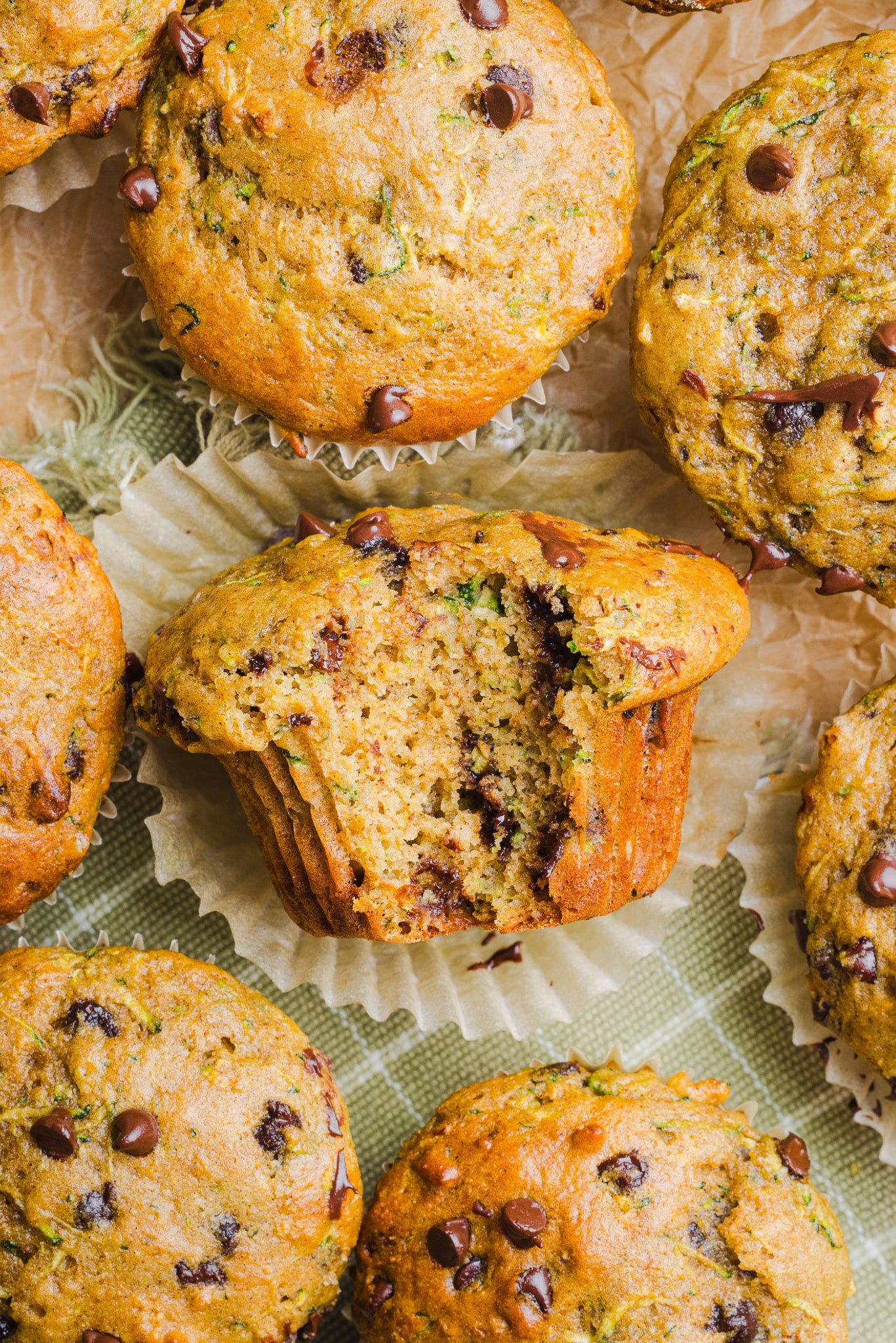 Protein zucchini muffins on a countertop with a bite taken out of one.