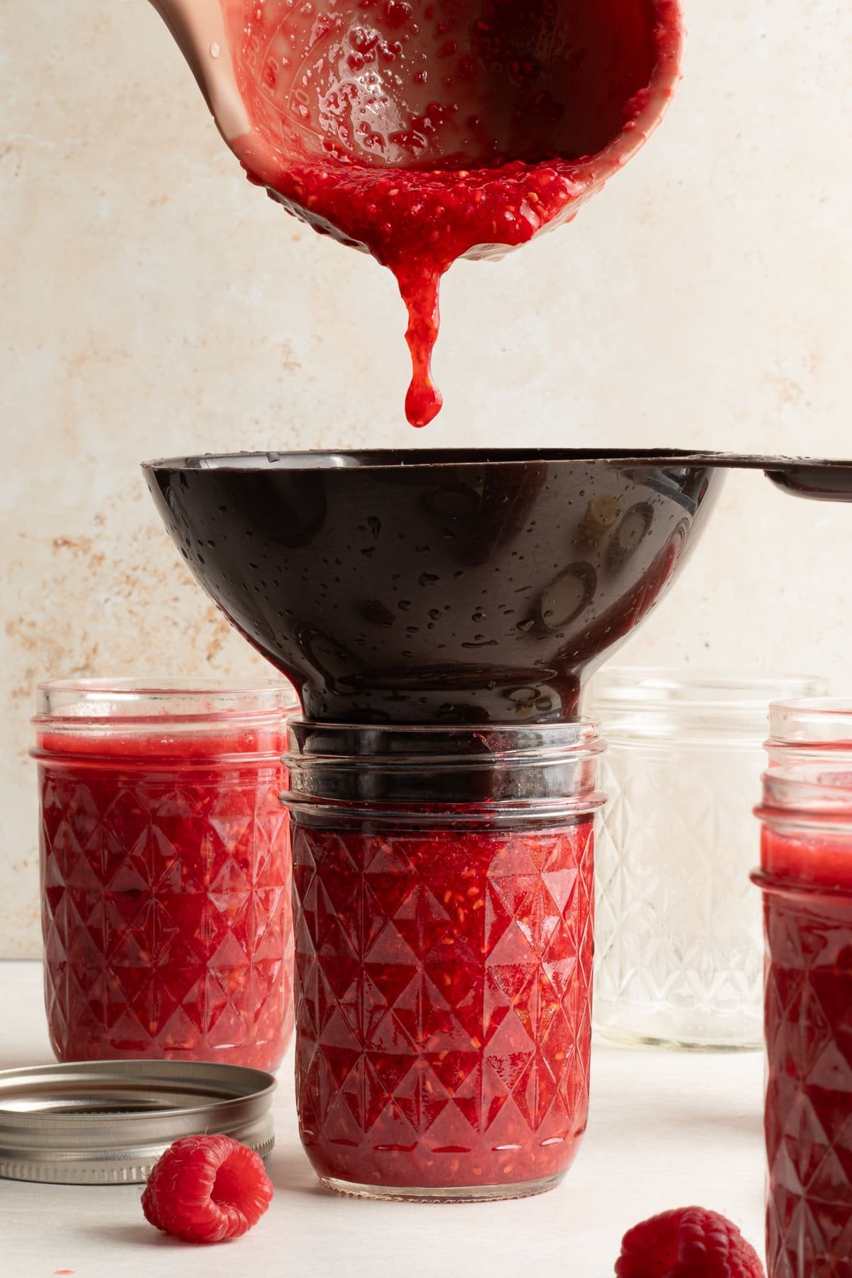 Raspberry freezer jam being poured into jars.