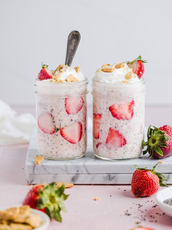 Strawberry cheesecake overnight oats with whipped cream, crumbled graham crackers and strawberries.