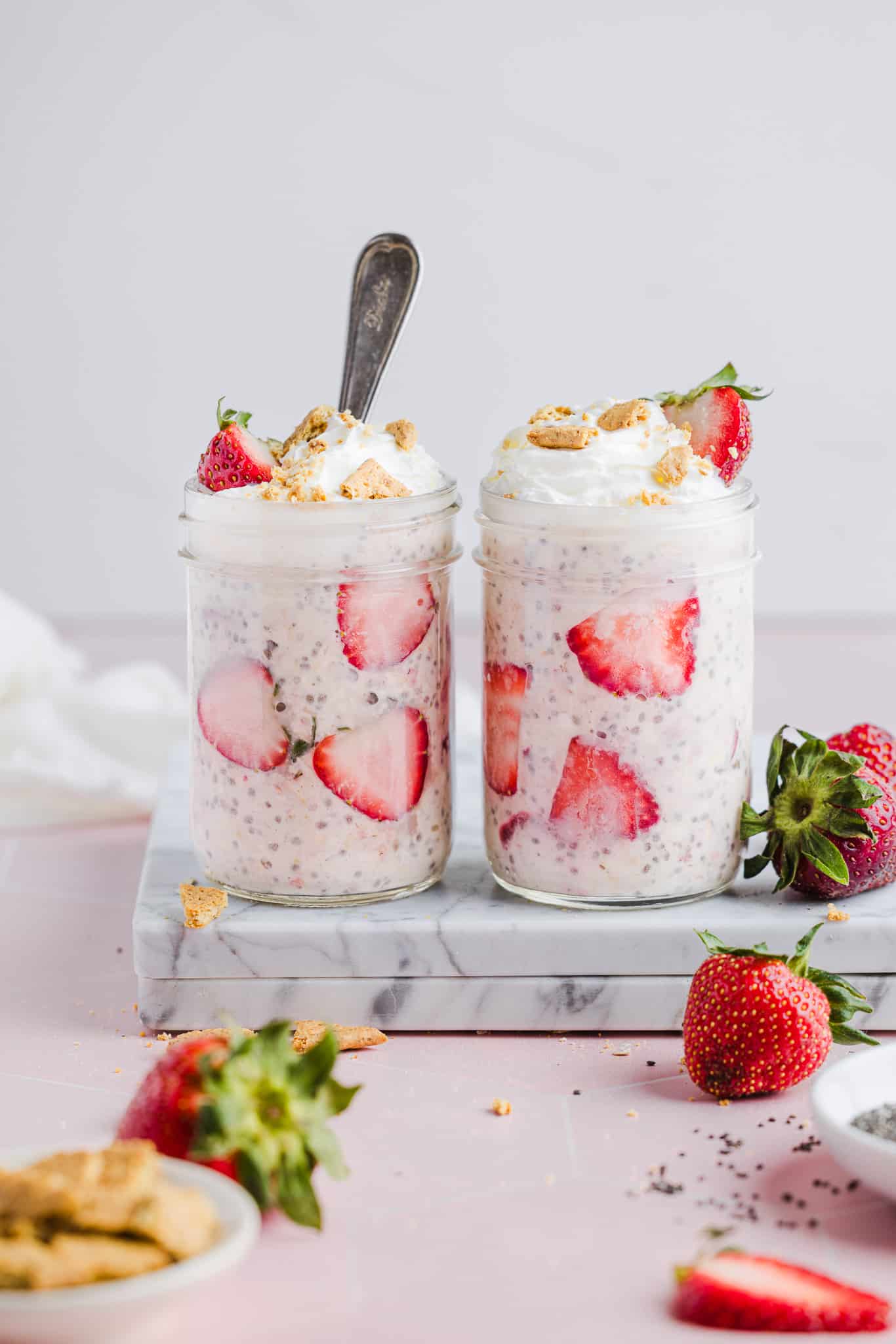 Strawberry cheesecake overnight oats with whipped cream, crumbled graham crackers and strawberries.