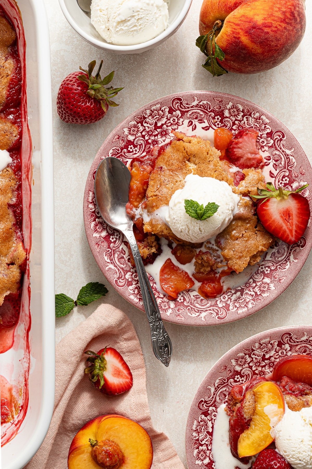 Strawberry peach cobbler on a plate with vanilla ice cream.