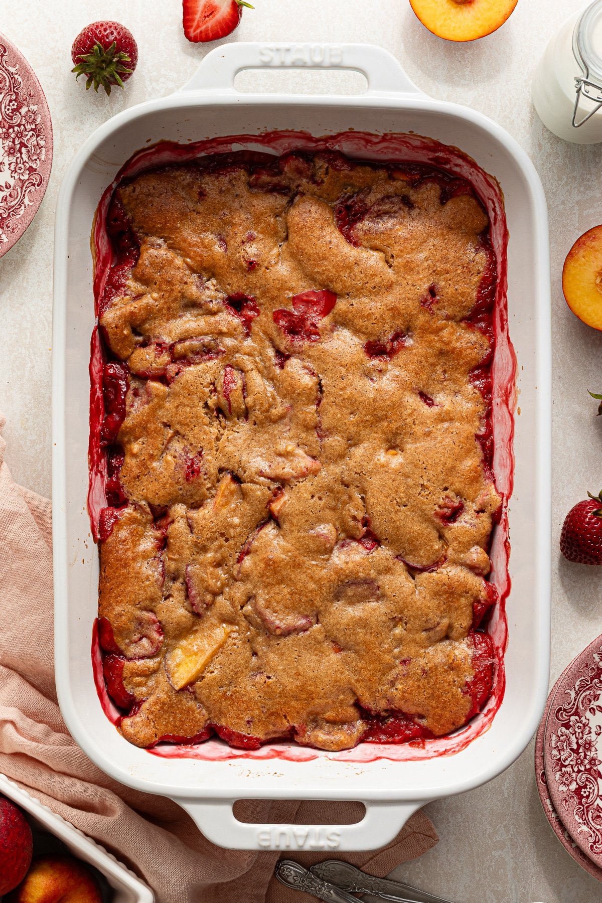 Strawberry peach cobbler baked in a white dish.
