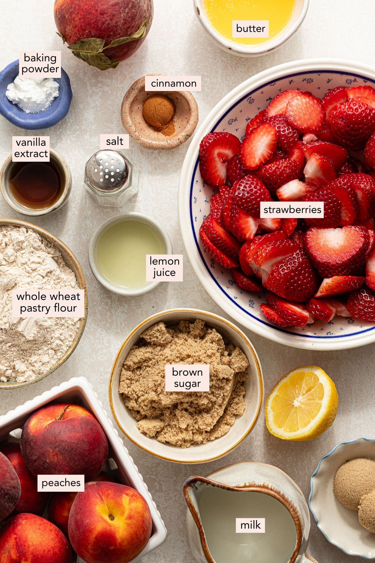 Ingredients for strawberry peach cobbler on a countertop with labels.