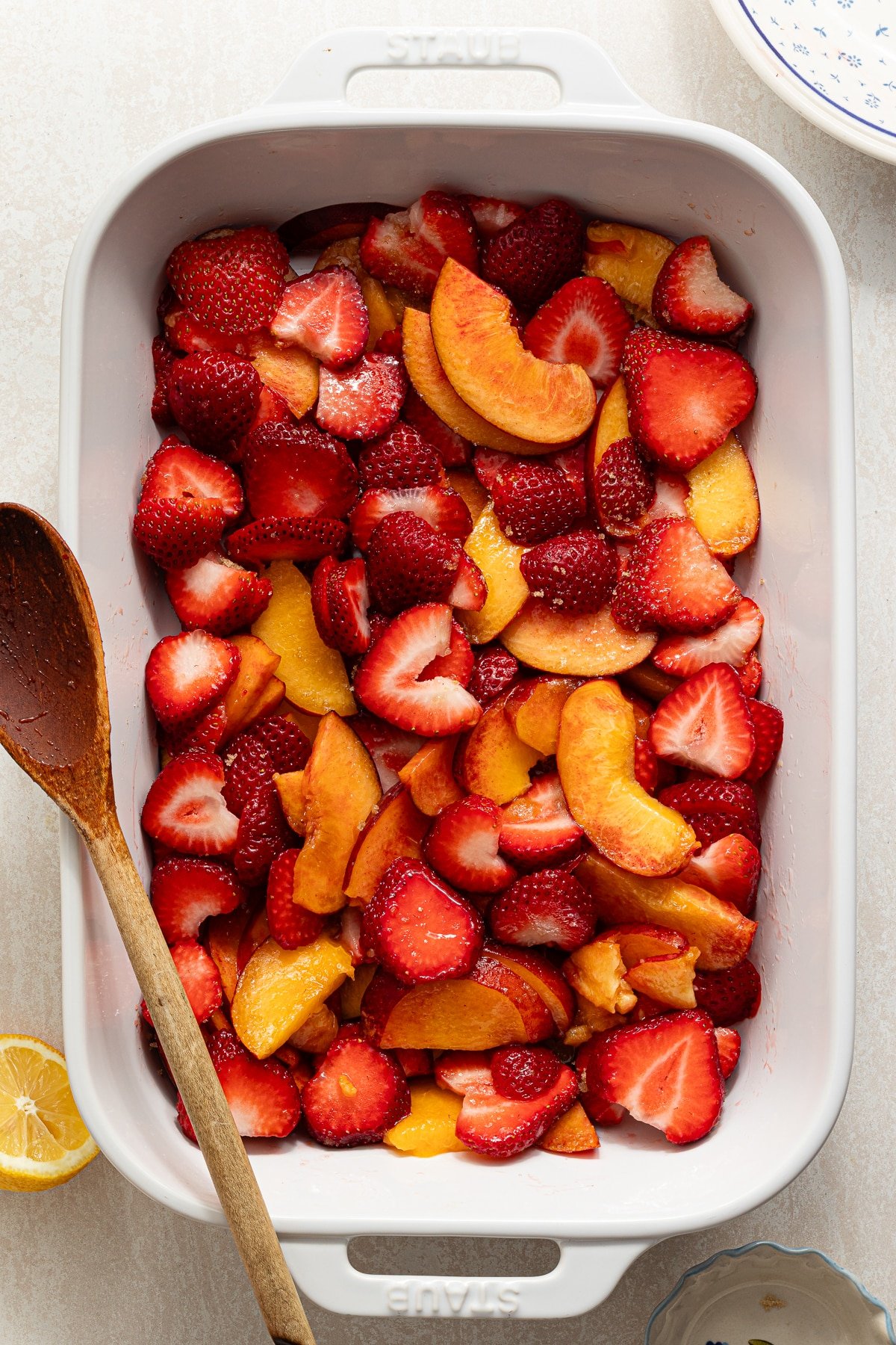 Strawberries and peaches mixed in a baking dish with brown sugar and lemon juice.