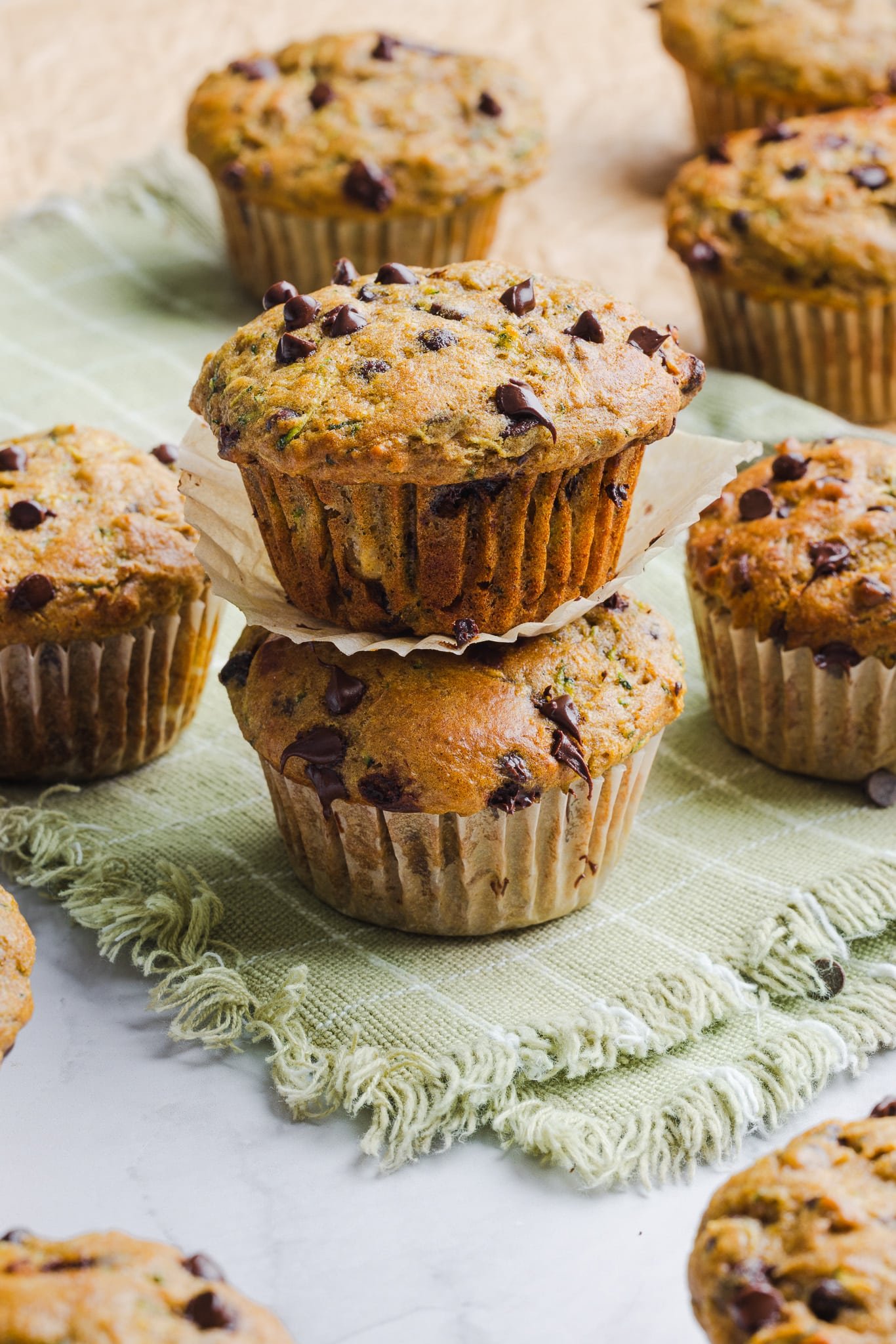Two stacked zucchini protein muffins on a green dish towel.