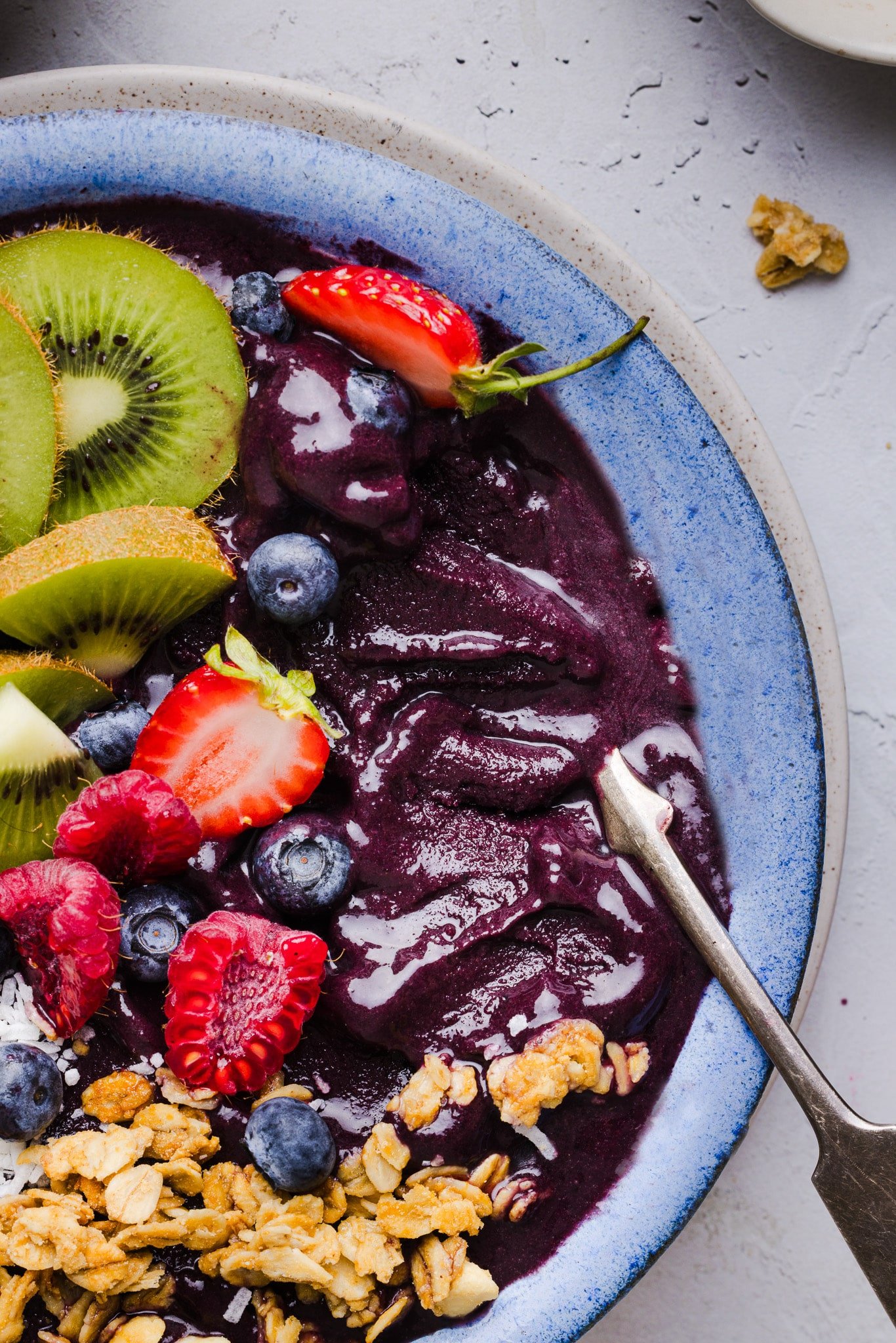 Close-up image of an acai bowl topped with fresh fruit, coconut flakes, and granola. 