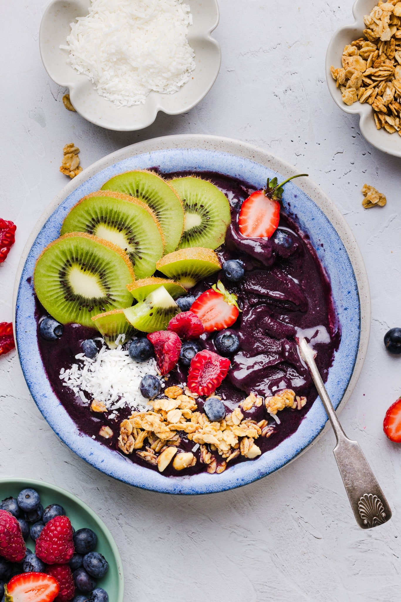 Overhead image of an acai bowl topped with fresh fruit, coconut flakes, and granola. 