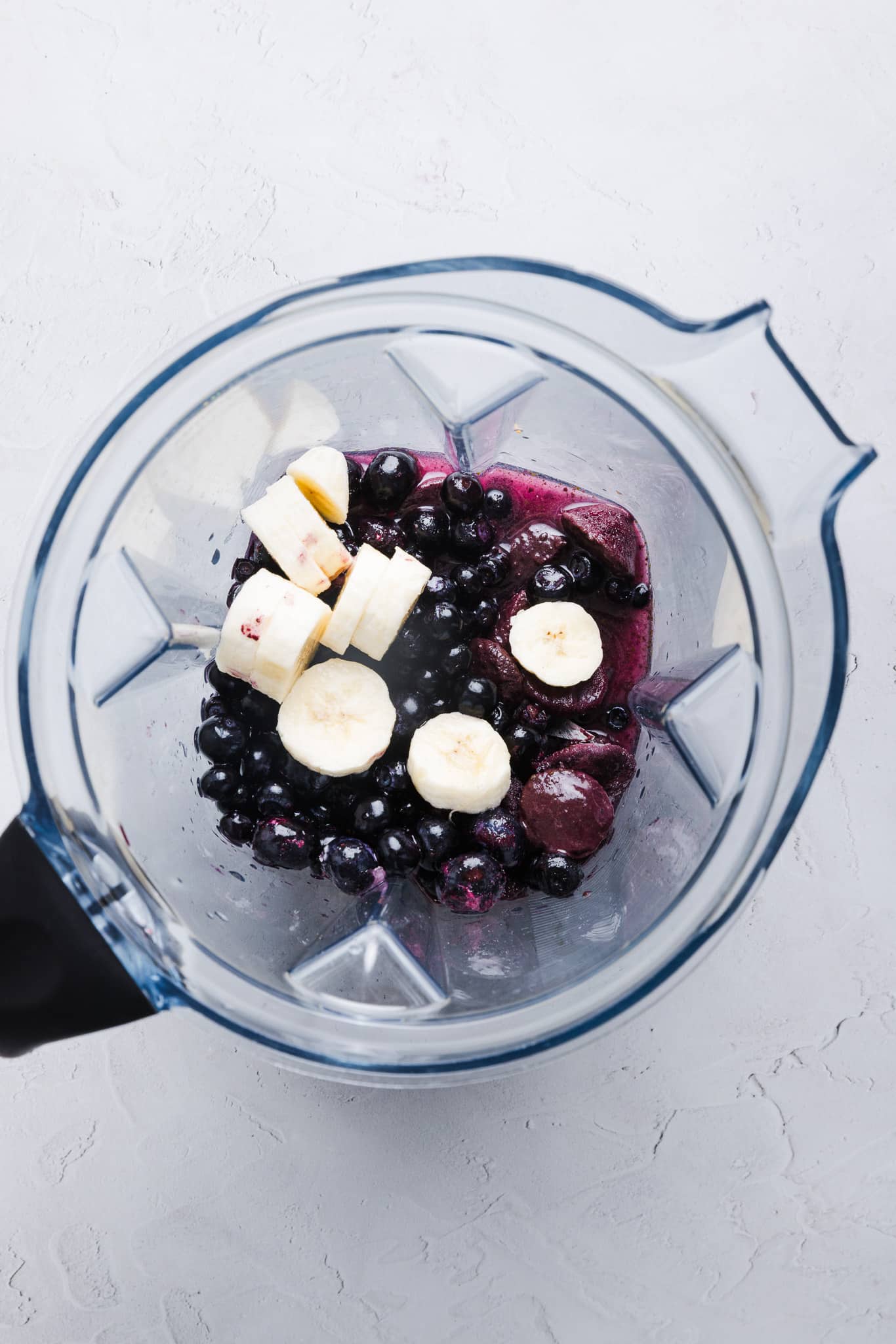 Acai, blueberries, banana slices, and coconut water in a blender. 