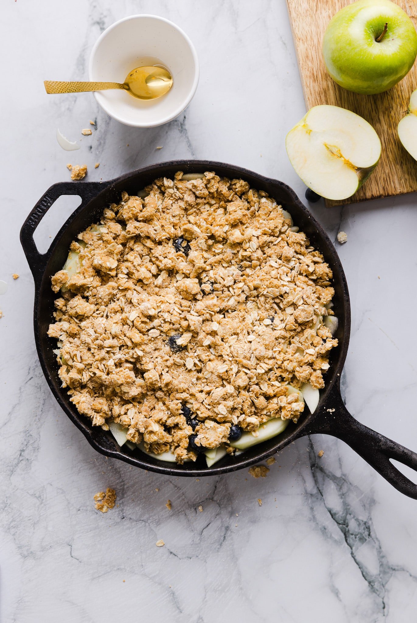 Spreading a crumble topping over honey-sweetened apples and blueberries.