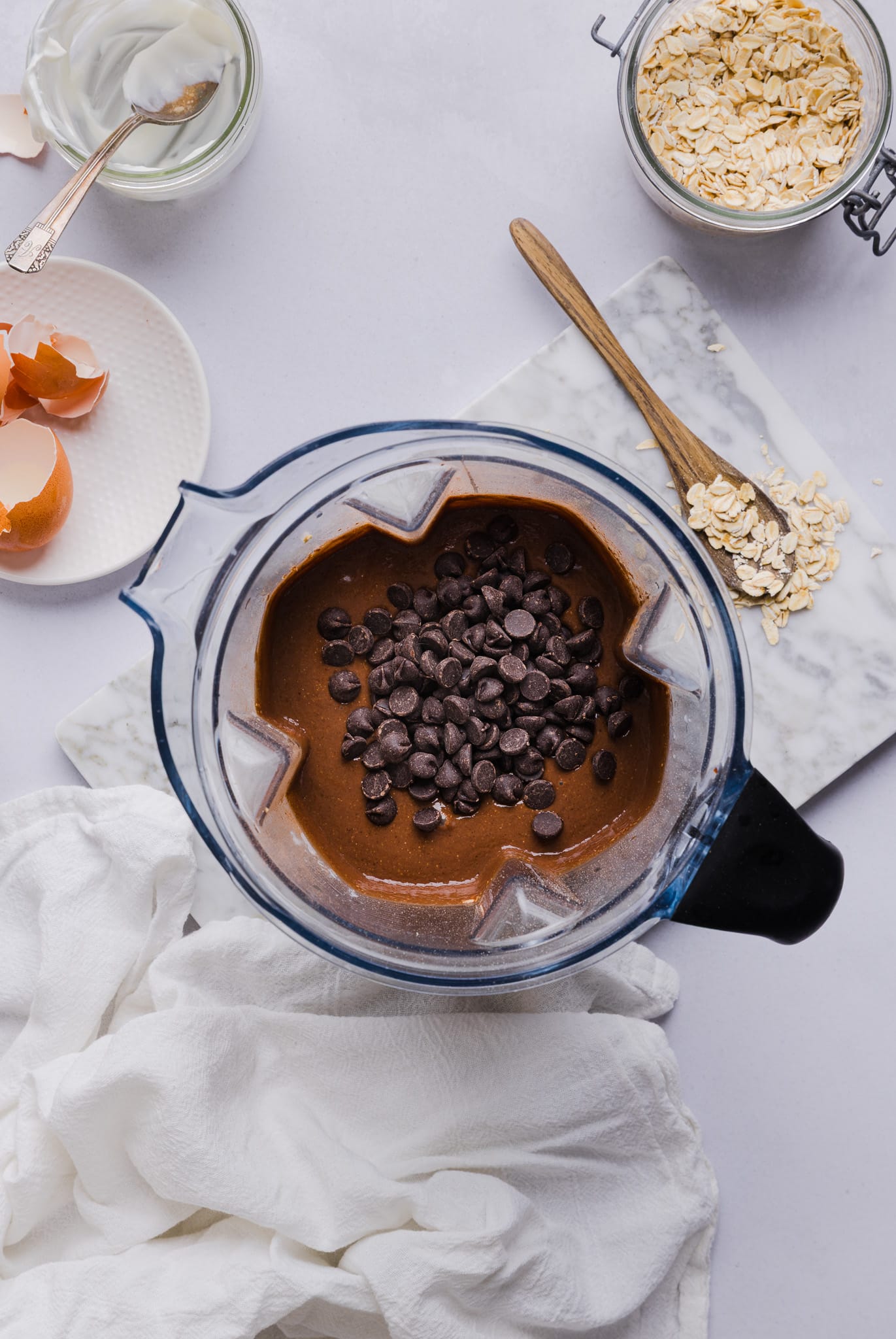 Ingredients for chocolate baked oats blended in a blender and chocolate chips stirred in.
