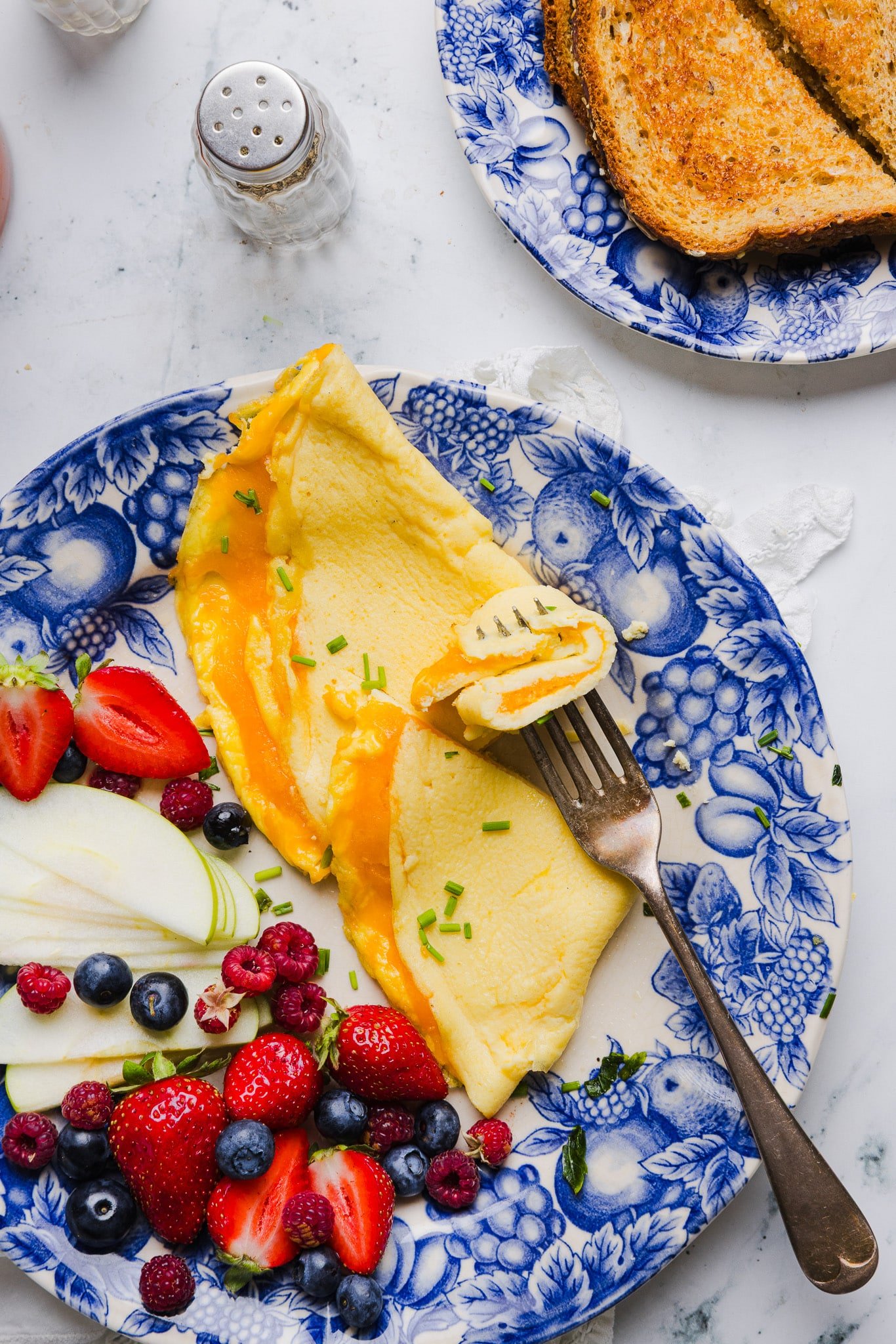 This easy cottage cheese omelette is loaded with creamy, salty cottage cheese and sharp cheddar. It's a protein powerhouse! A fork taking a bite from a cottage cheese omelette.