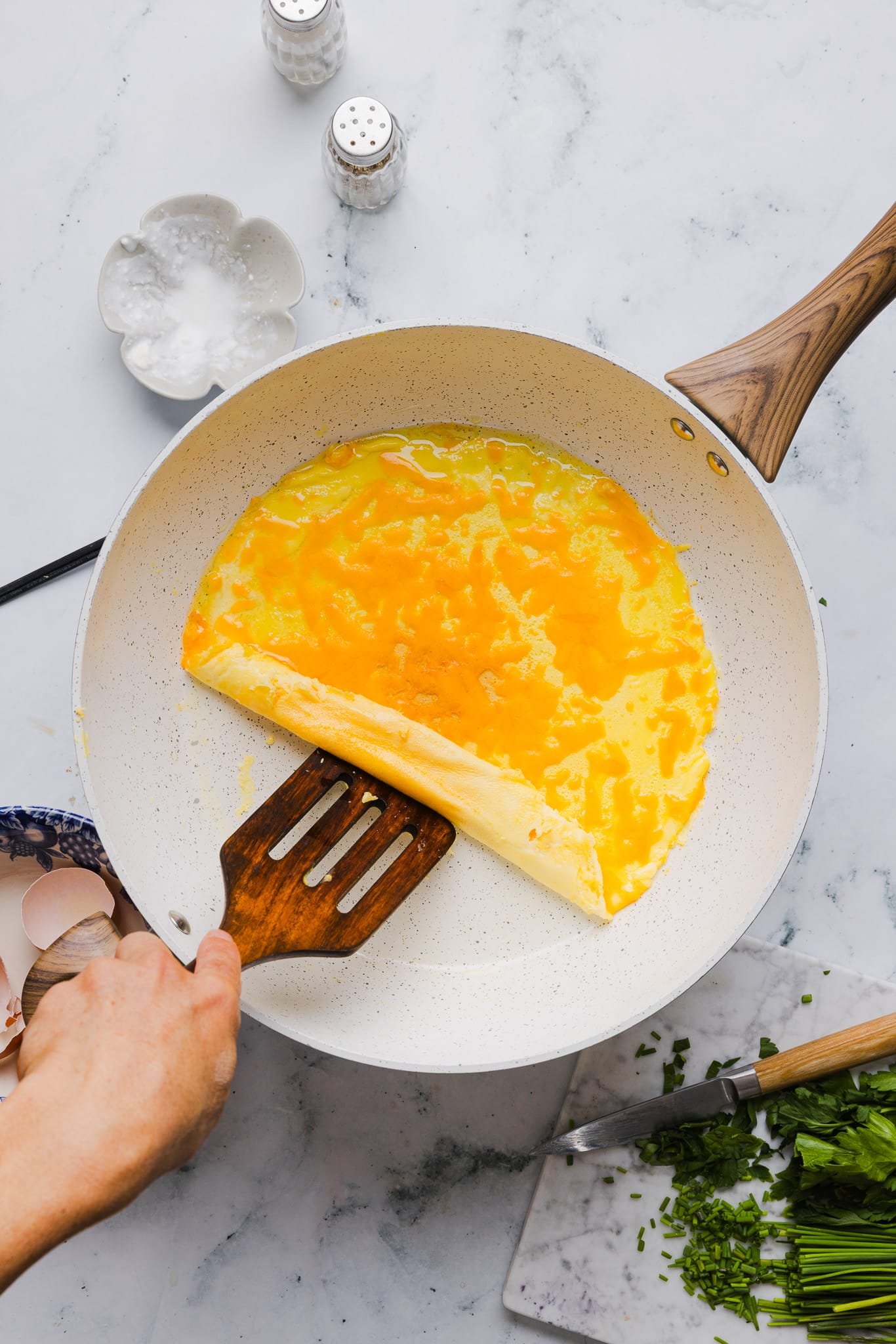 Folding a cottage cheese omelette over a cheddar cheese filling.