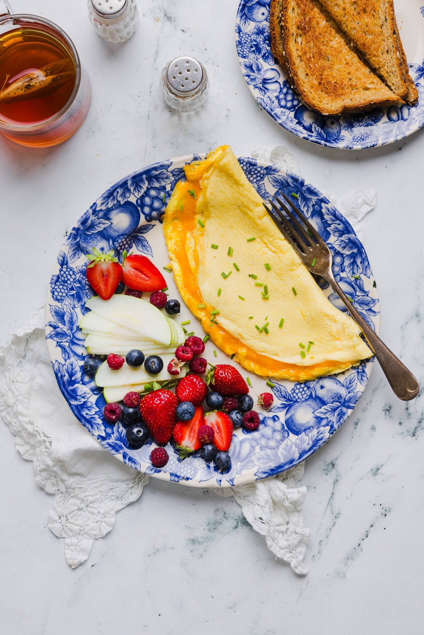 Overhead image of a cottage cheese omelette on a plate with fresh fruit.