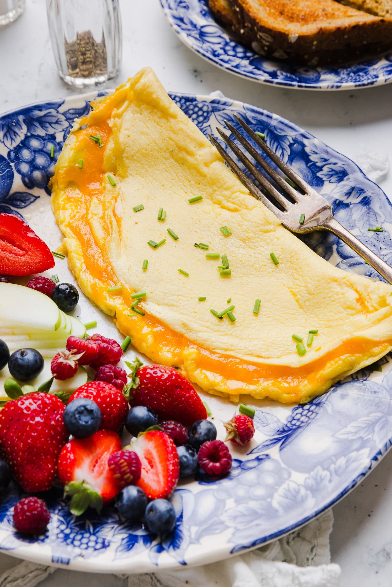 A cottage cheese omelette on a plate with fresh fruit.