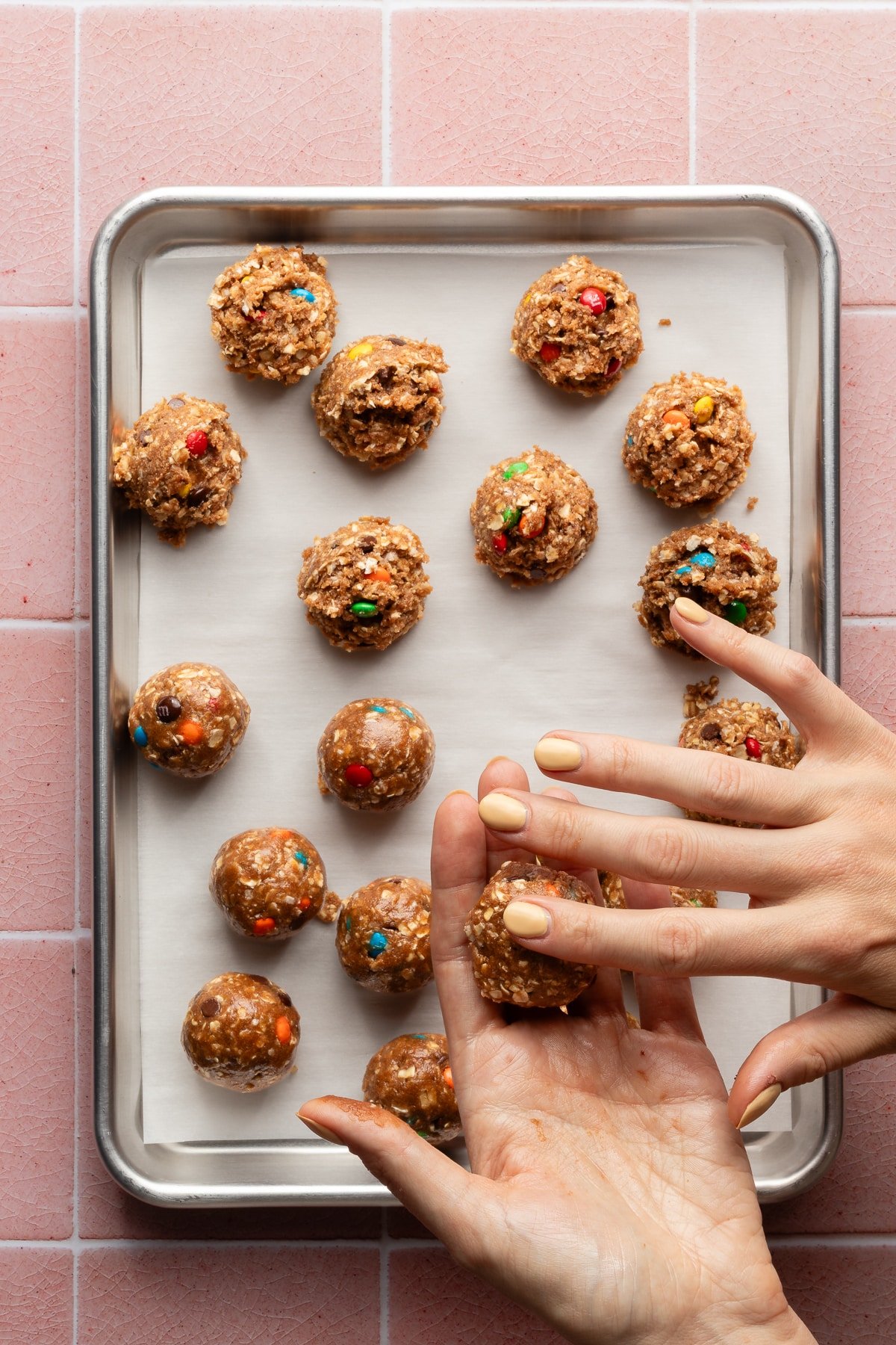 Moster protein balls being rolled on a lined baking sheet.