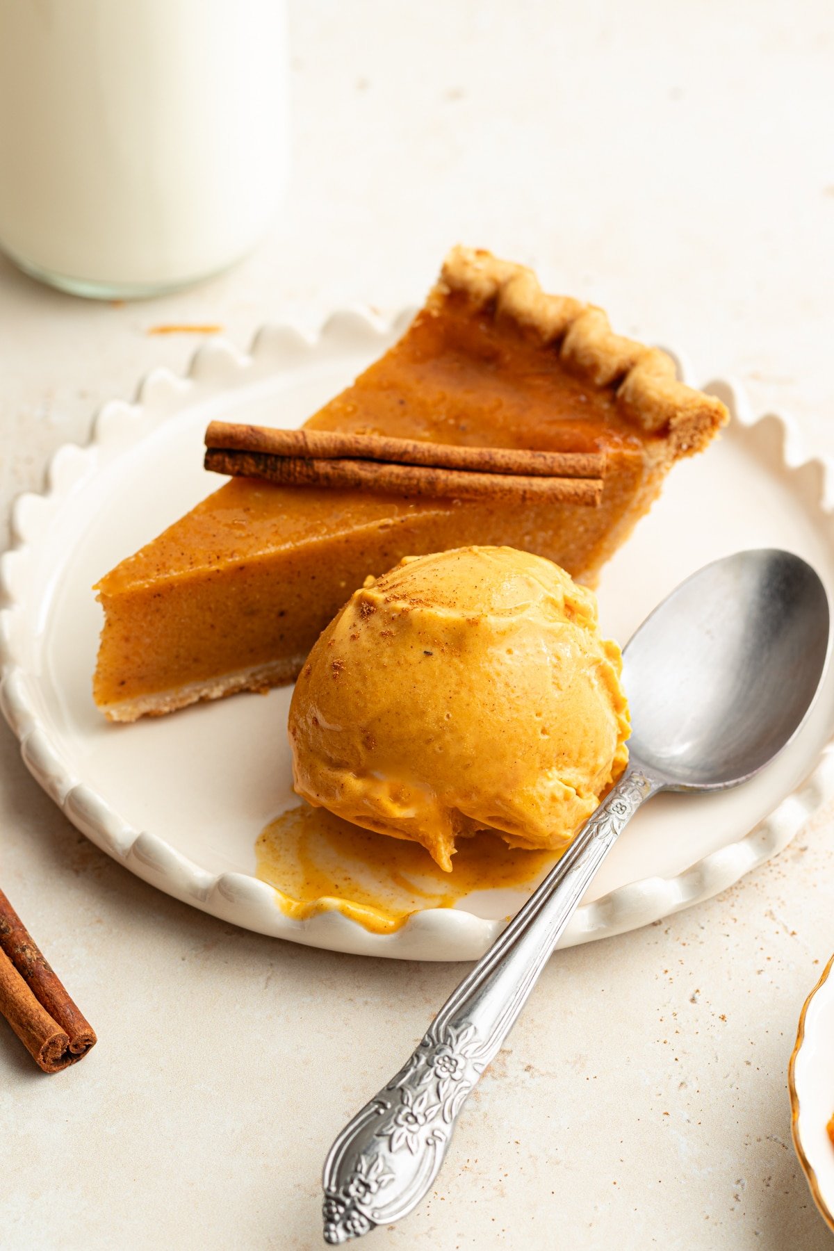 A scoop of Ninja Creami pumpkin ice cream with a slice of pumpkin pie.