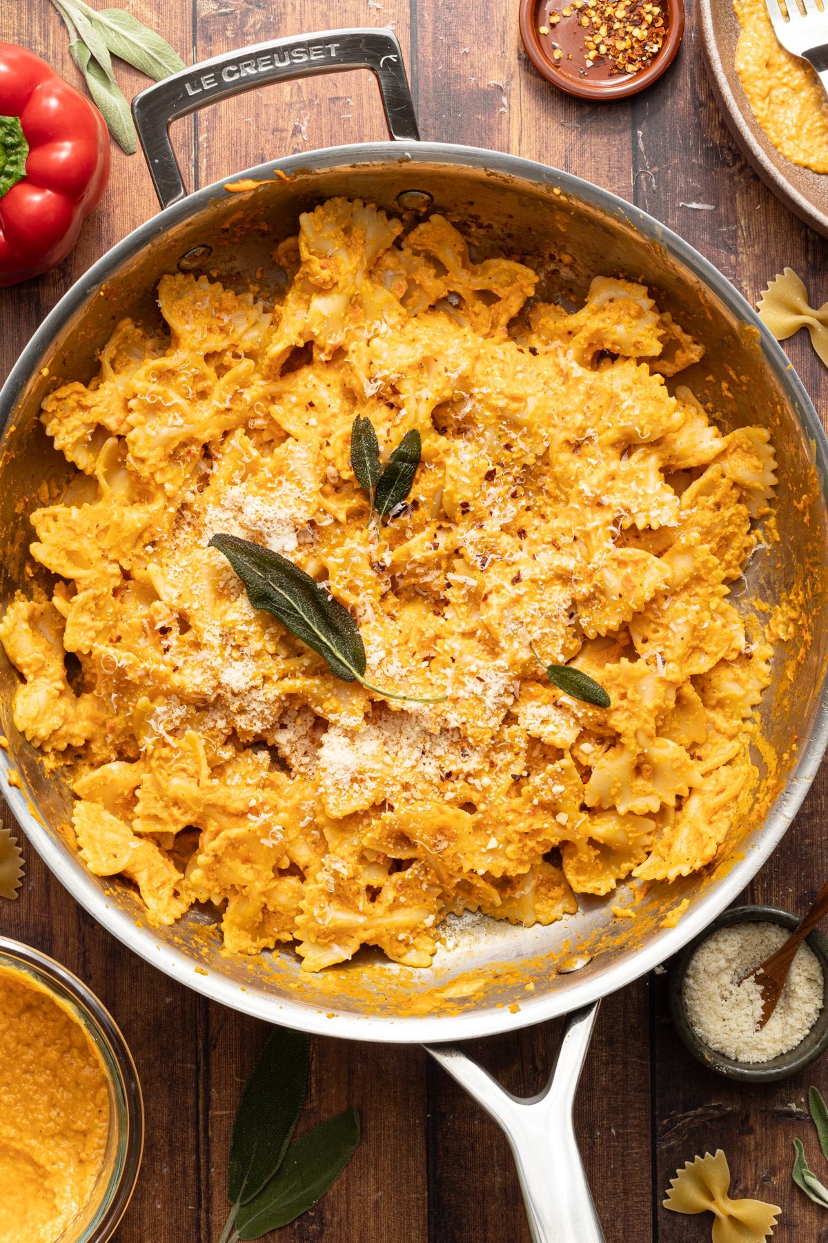 Pasta tossed in protein pumpkin pasta sauce in a pan and garnished with sage.