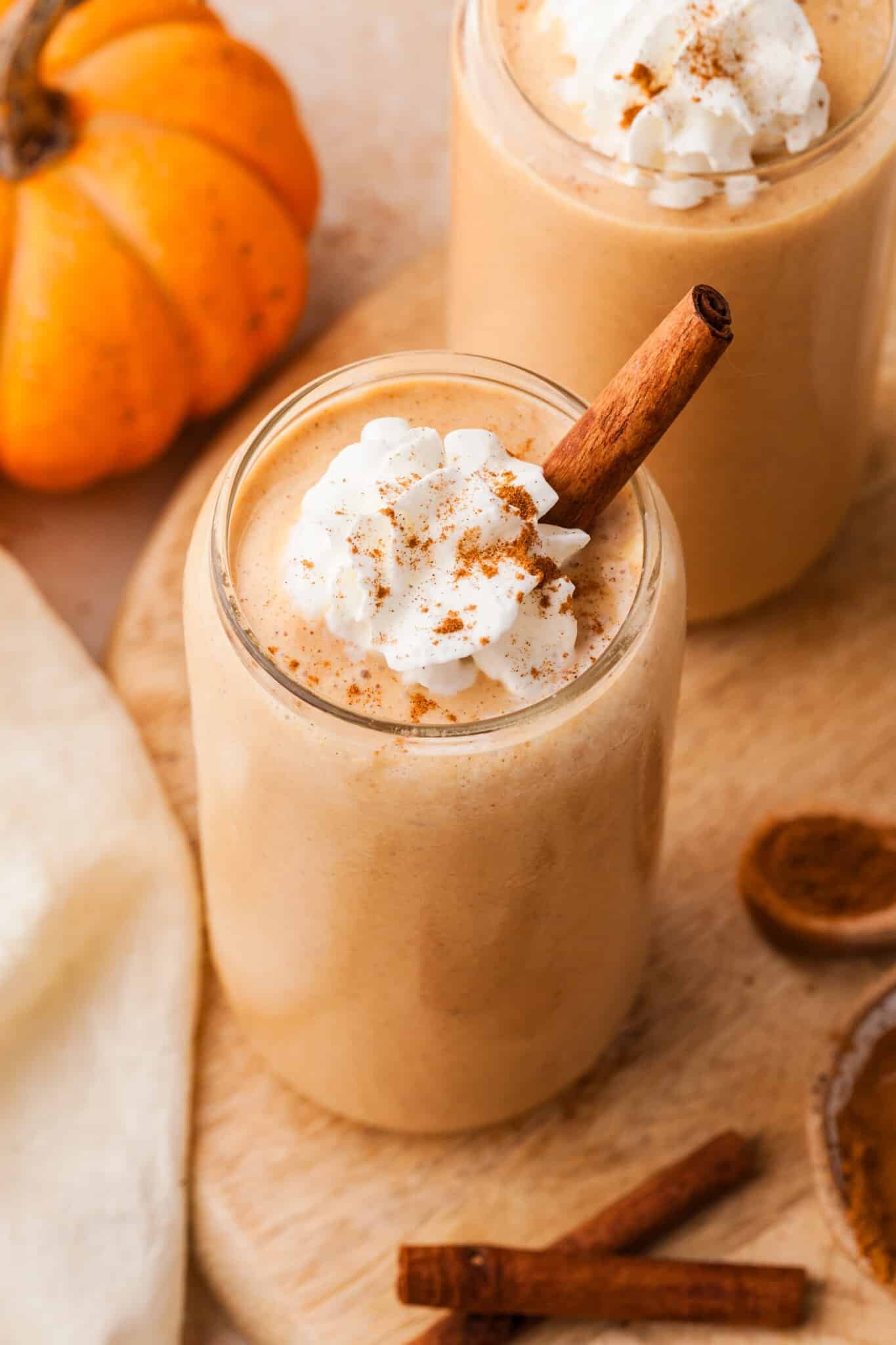Pumpkin protein smoothie topped with whipped cream and a cinnamon stick.