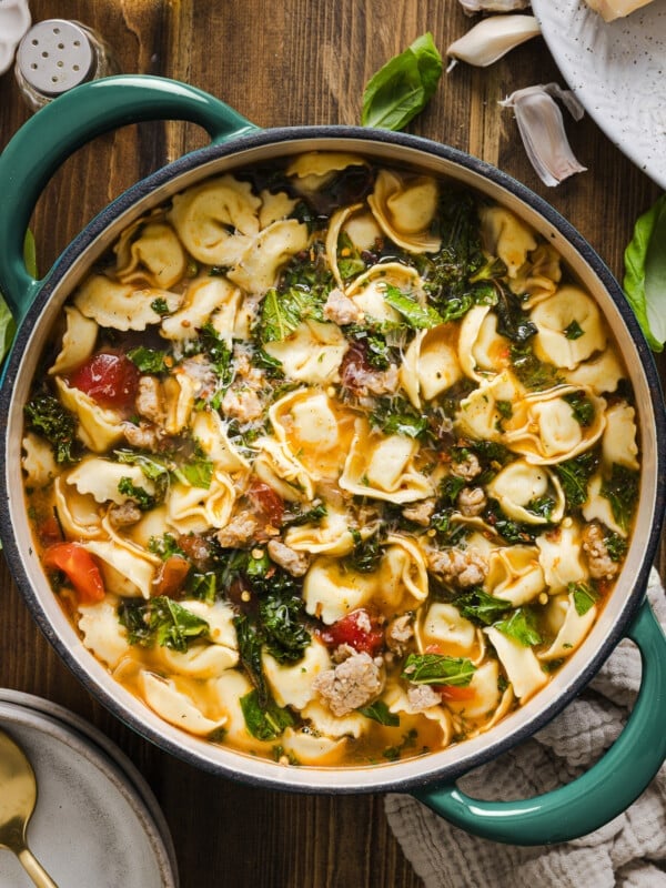 Kale and tortellini soup in a dutch oven on a wooden counter.