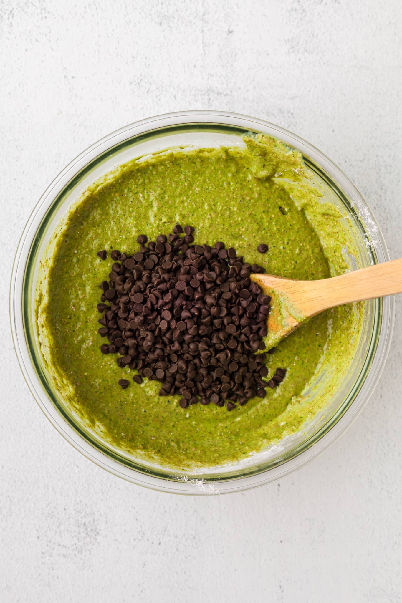 Chocolate chips being added to spinach banana muffin batter.