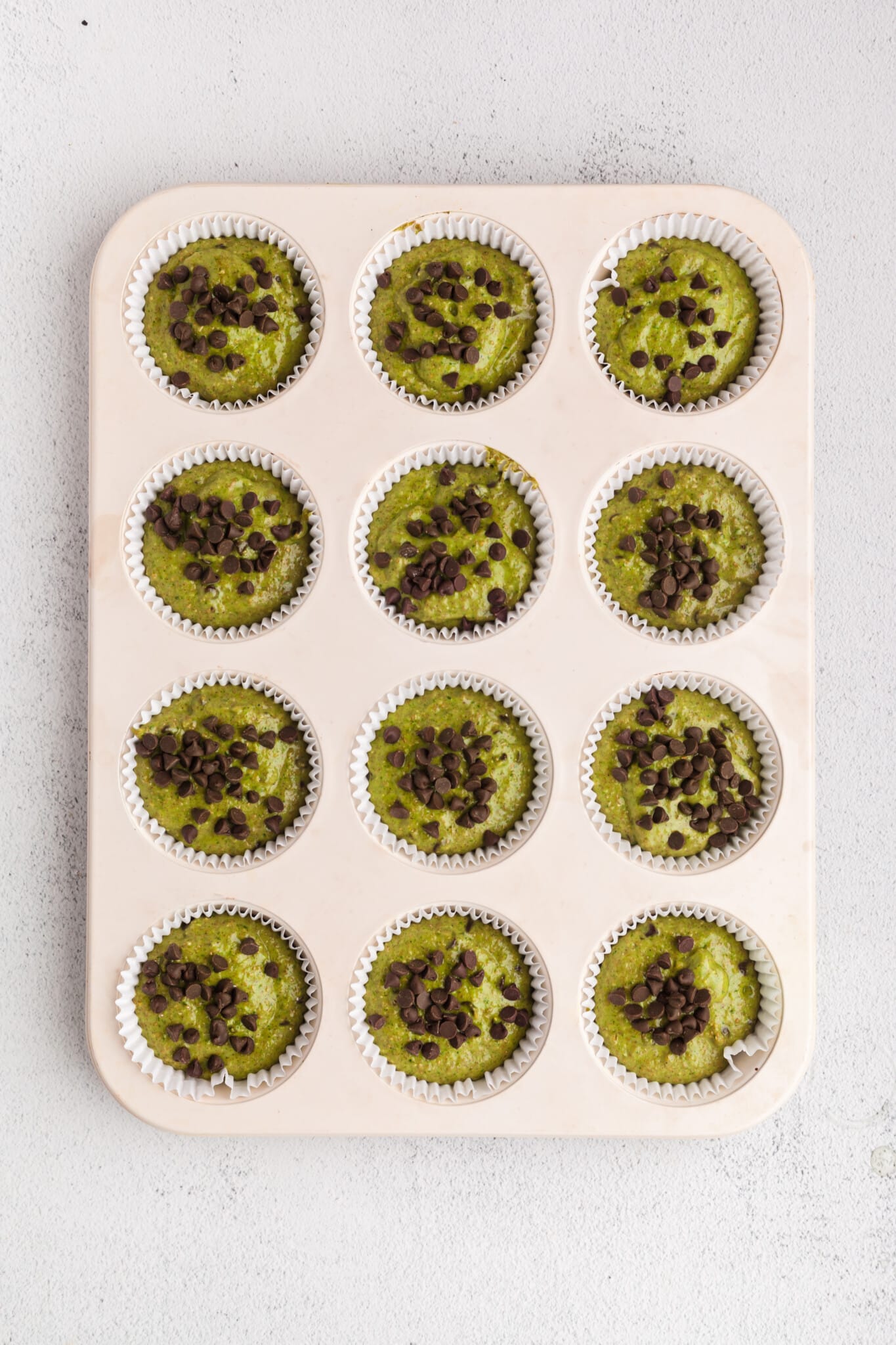 Spinach banana muffin batter in a muffin pan.