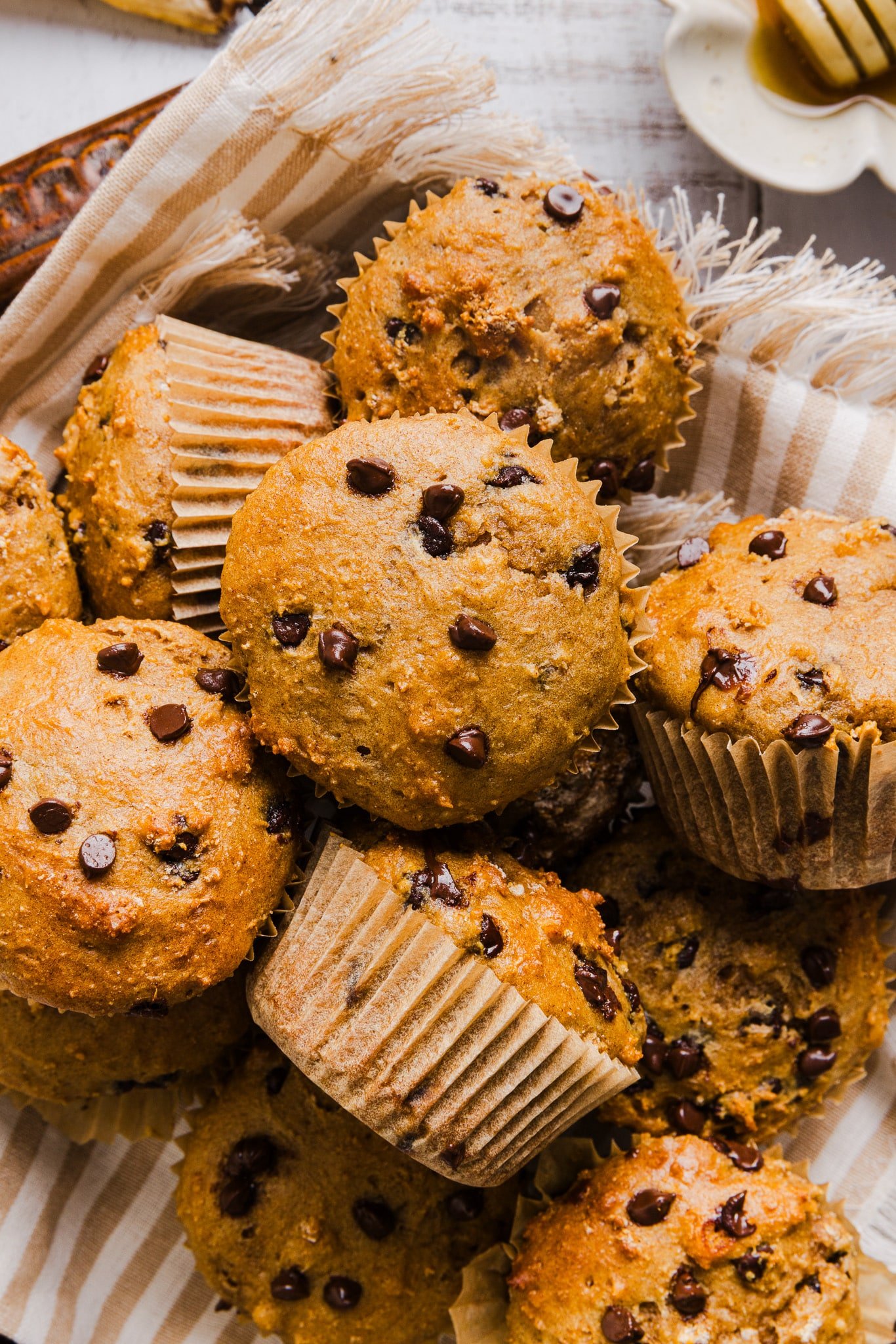 Cottage cheese banana muffins with mini chocolate chips in a pan with a stripped tea towel.