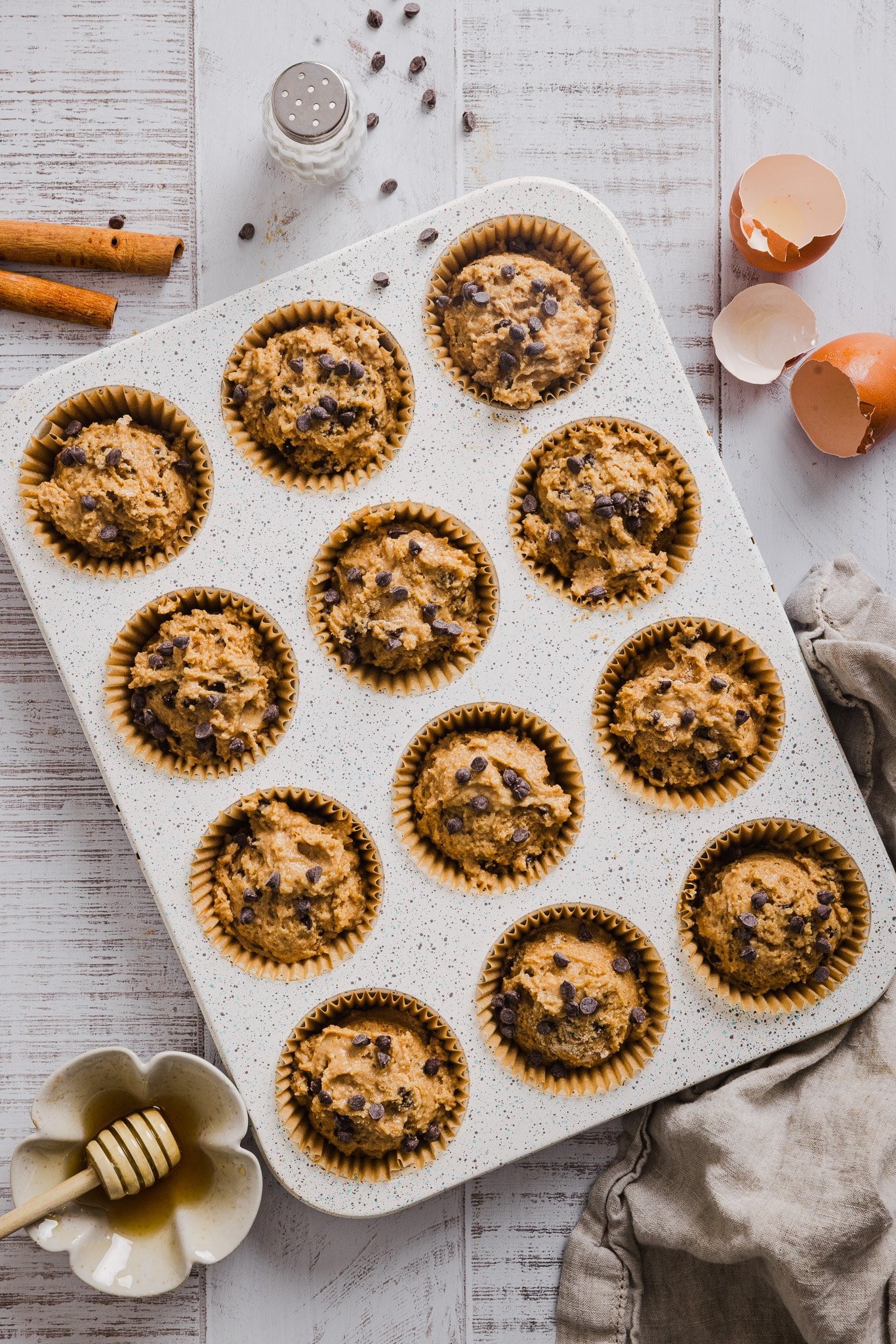 Banana and cottage cheese muffin batter with mini chocolate chips in a lined muffin tin.